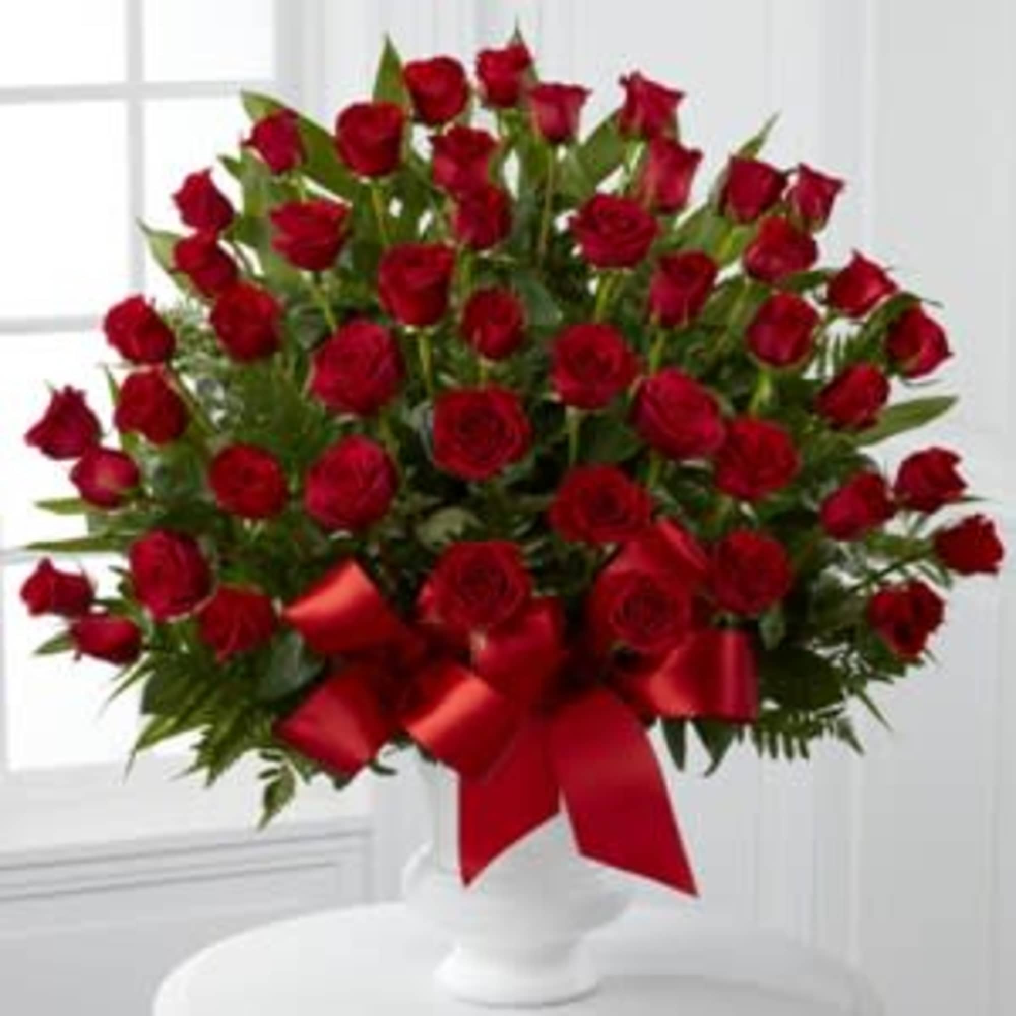 Large bouquet of red roses with a red ribbon in a white vase