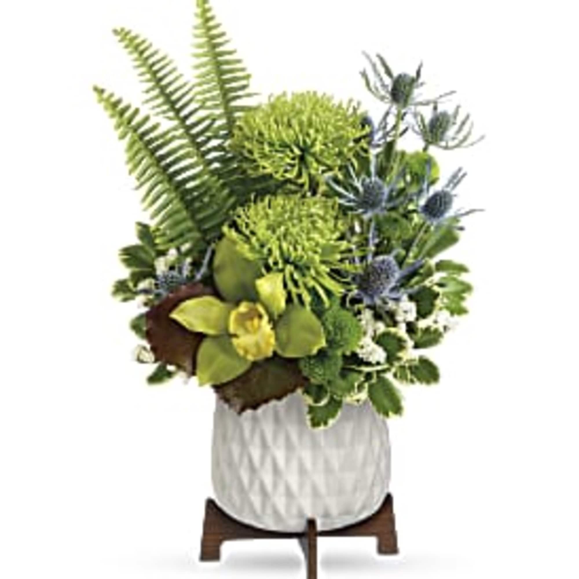 Modern green and blue floral arrangement with mums, orchids, and fern fronds in a white pot on a wooden stand