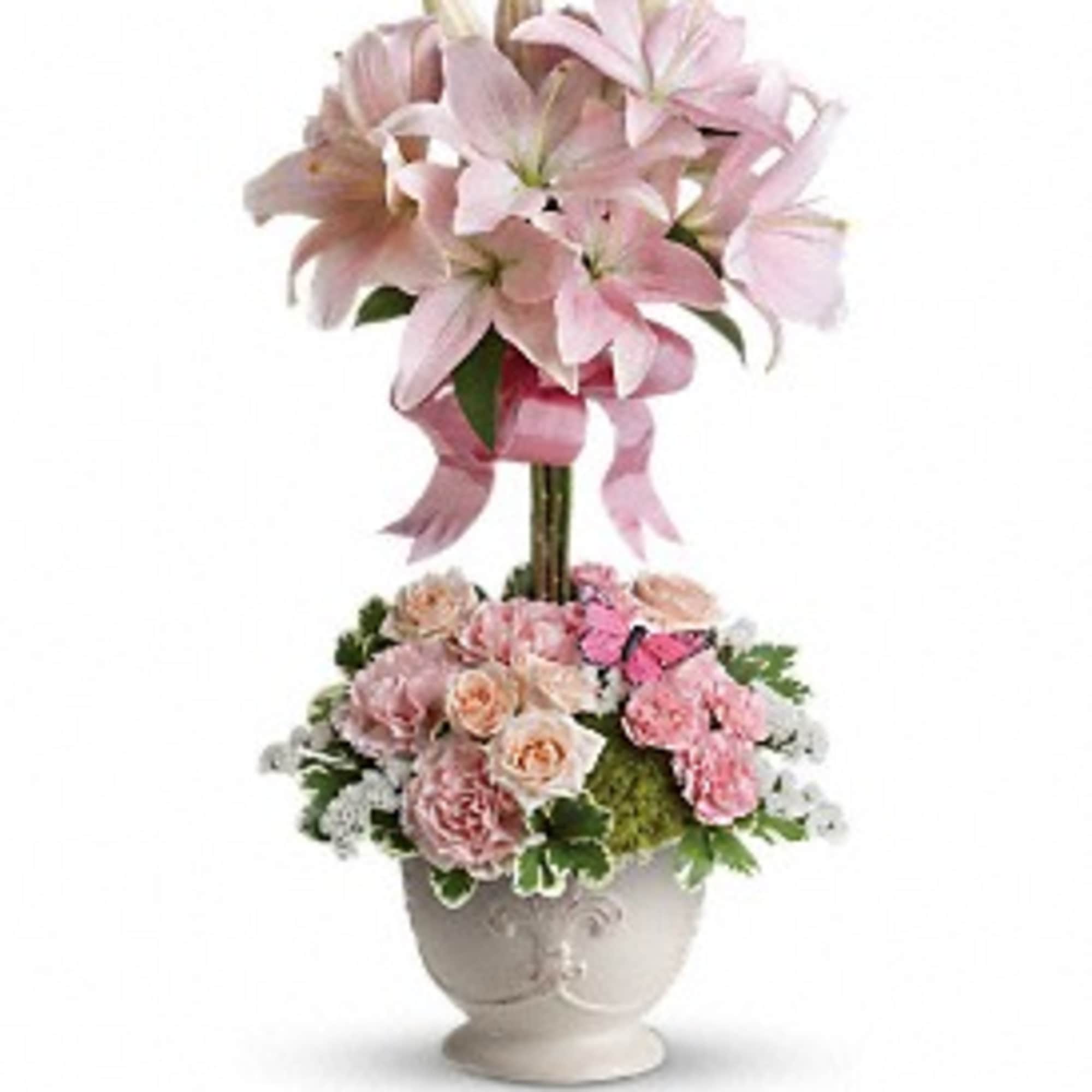 Topiary-style pink lily and rose arrangement in a white urn with a butterfly accent