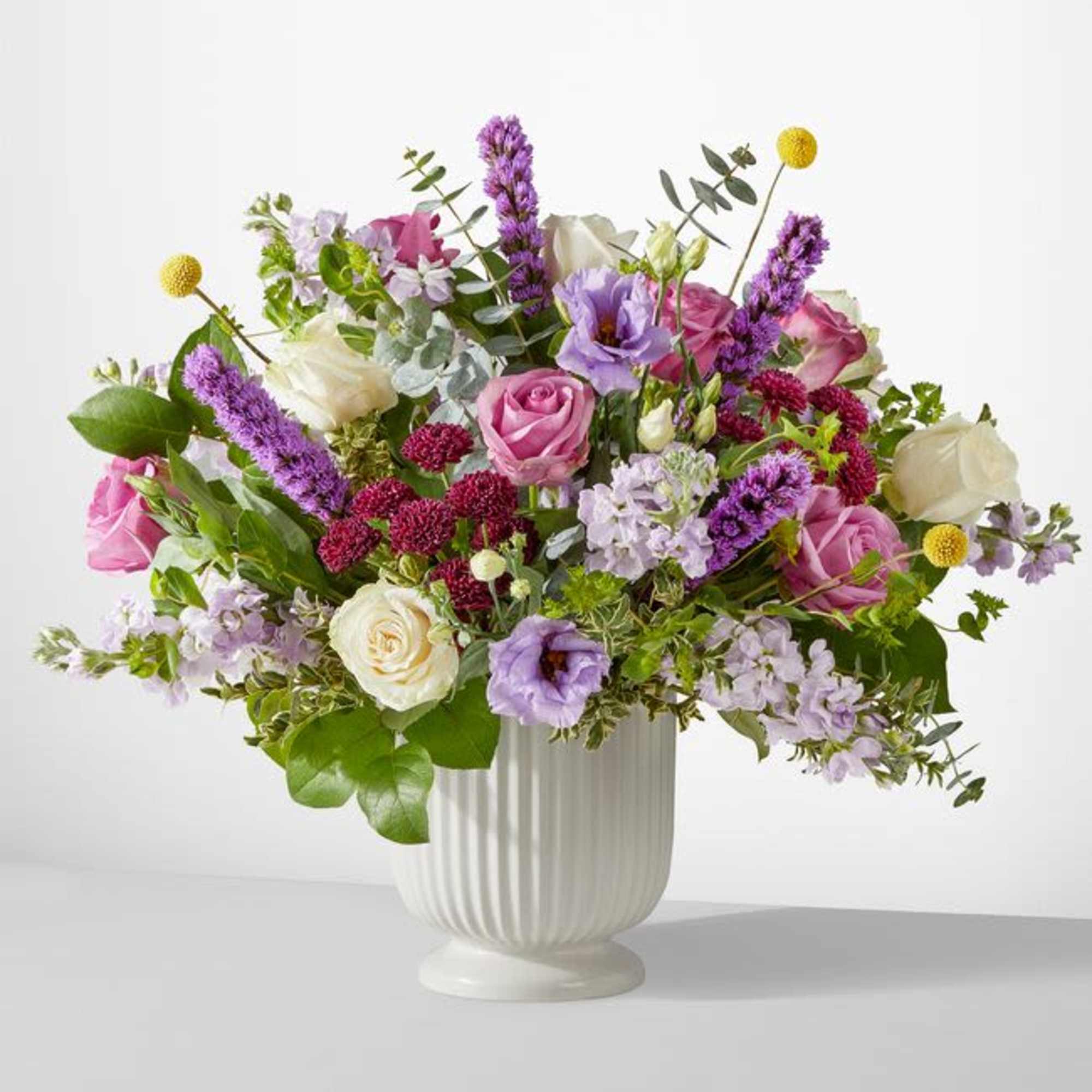 Mixed pink, white, and lavender flowers in a white vase