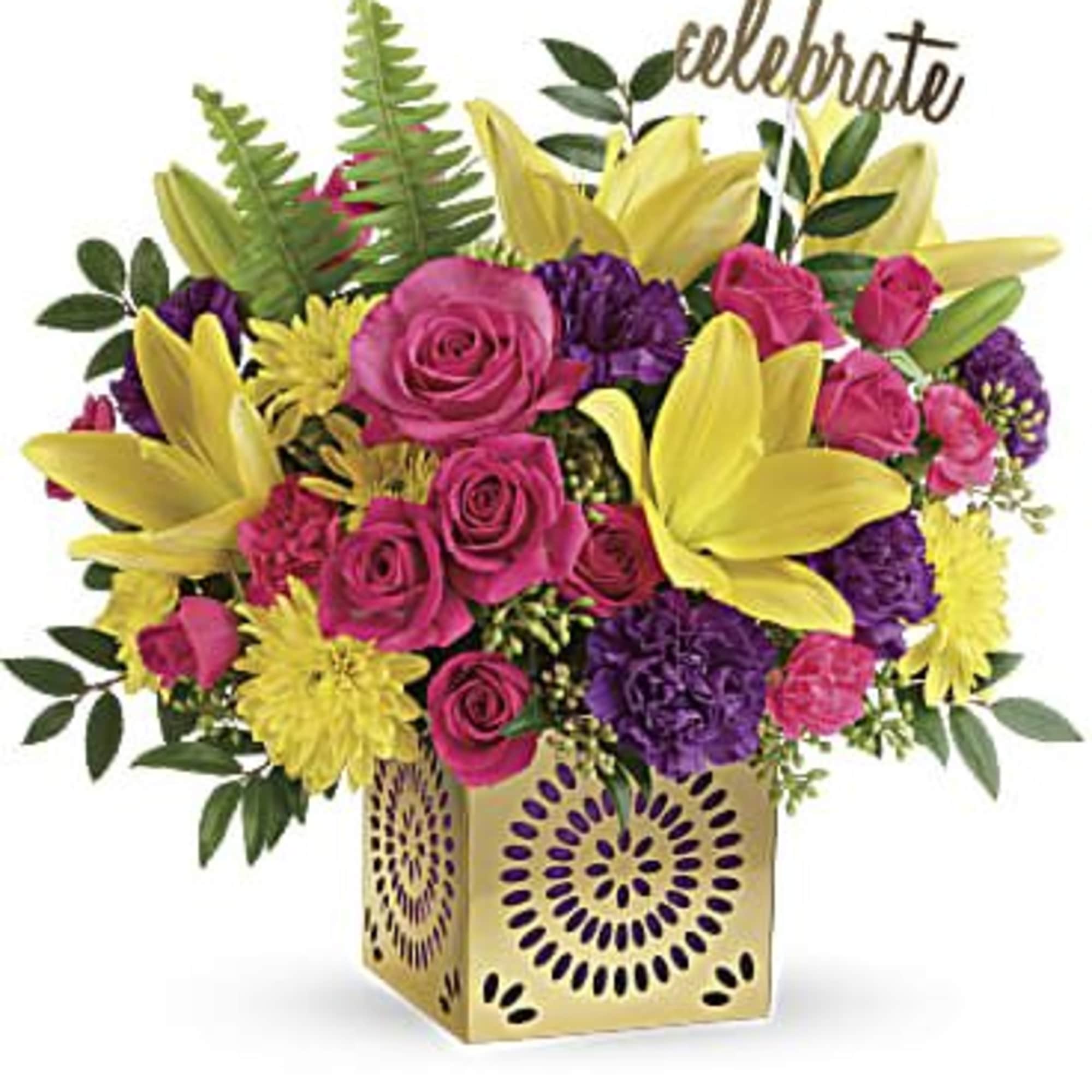 Pink roses and yellow lilies in a gold vase with a "celebrate" pick