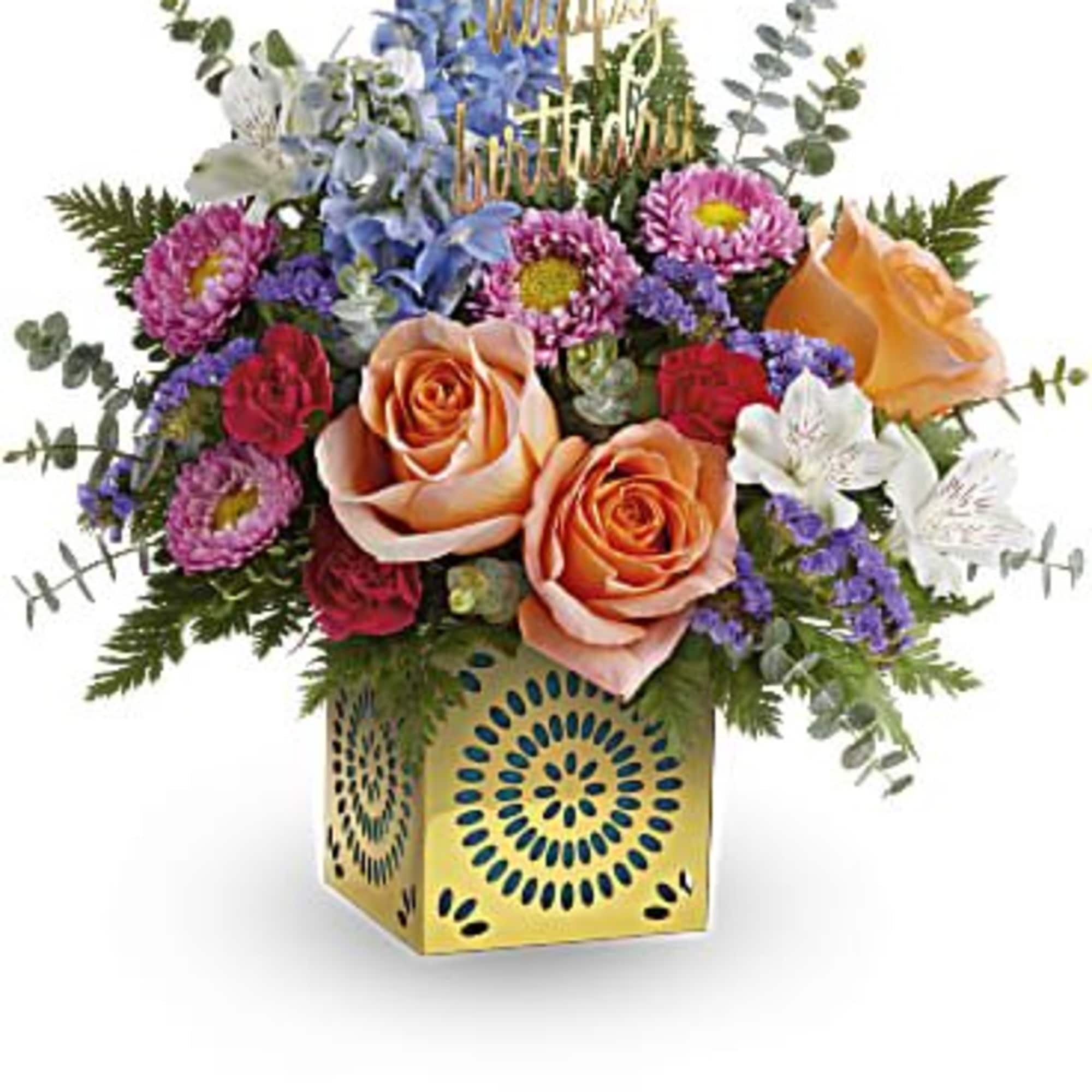 Colorful birthday flower arrangement with peach roses in a yellow cube vase and happy birthday pick