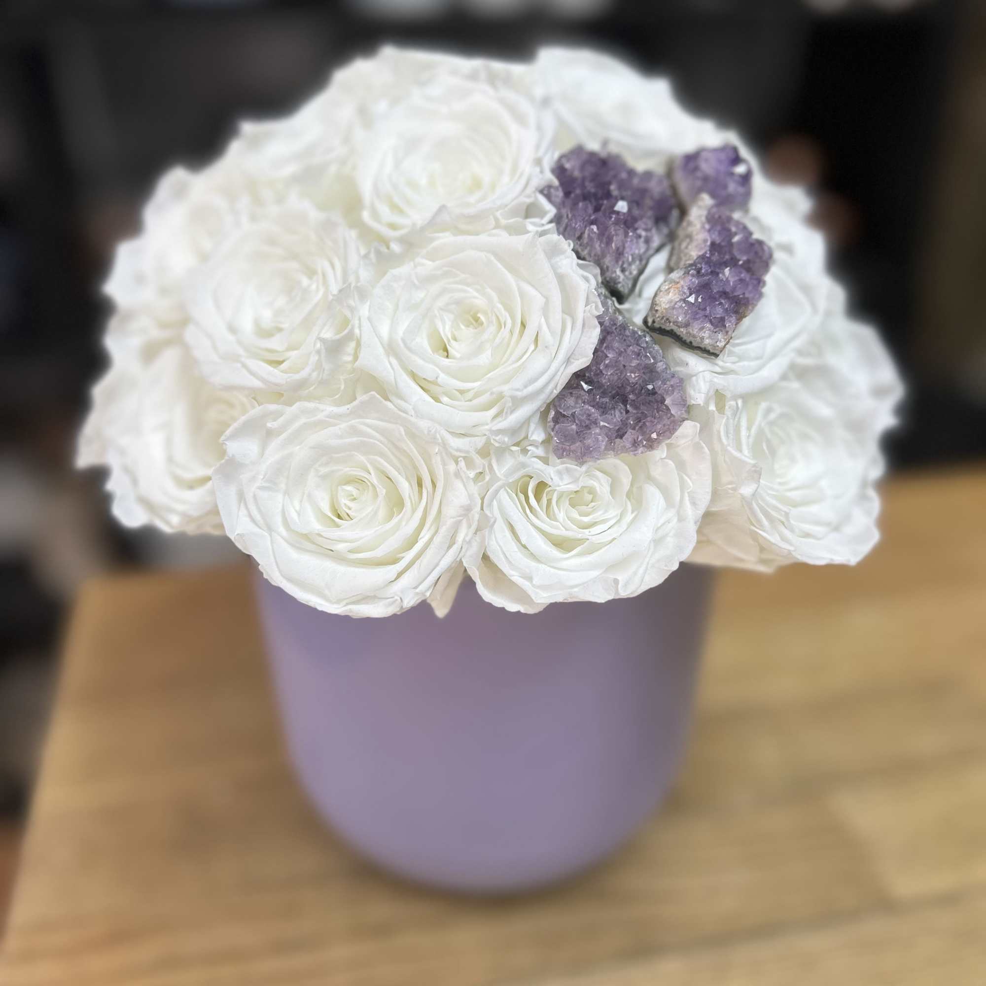 White roses arranged in a lavender hat box with purple crystals