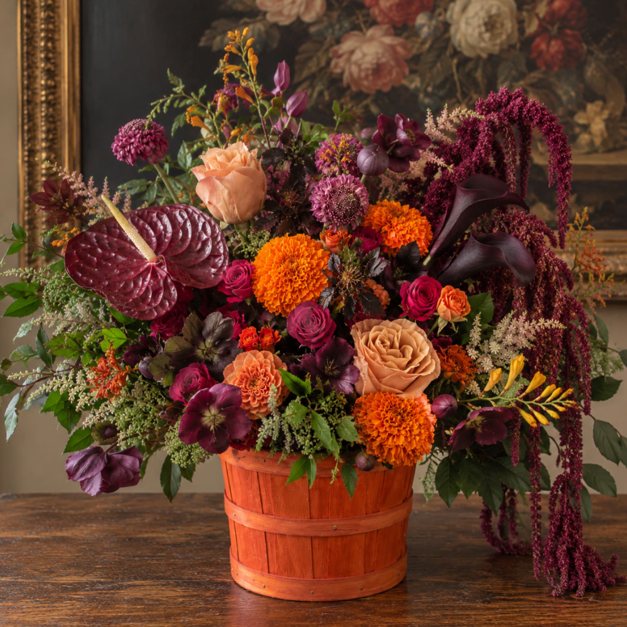 Mixed floral arrangement in an orange wooden basket with burgundy and orange blooms