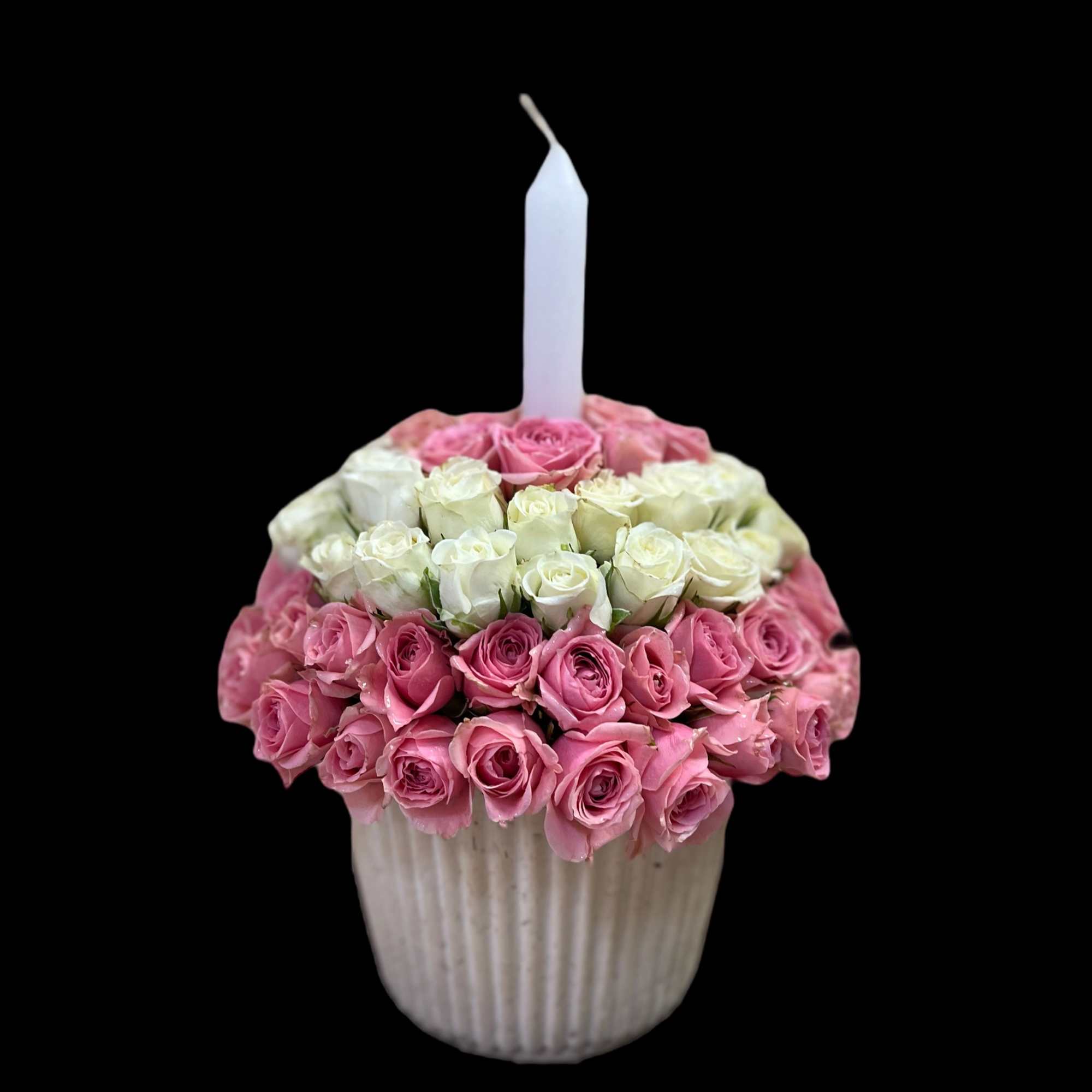 Pink and white roses arranged in a ribbed vase with a white candle