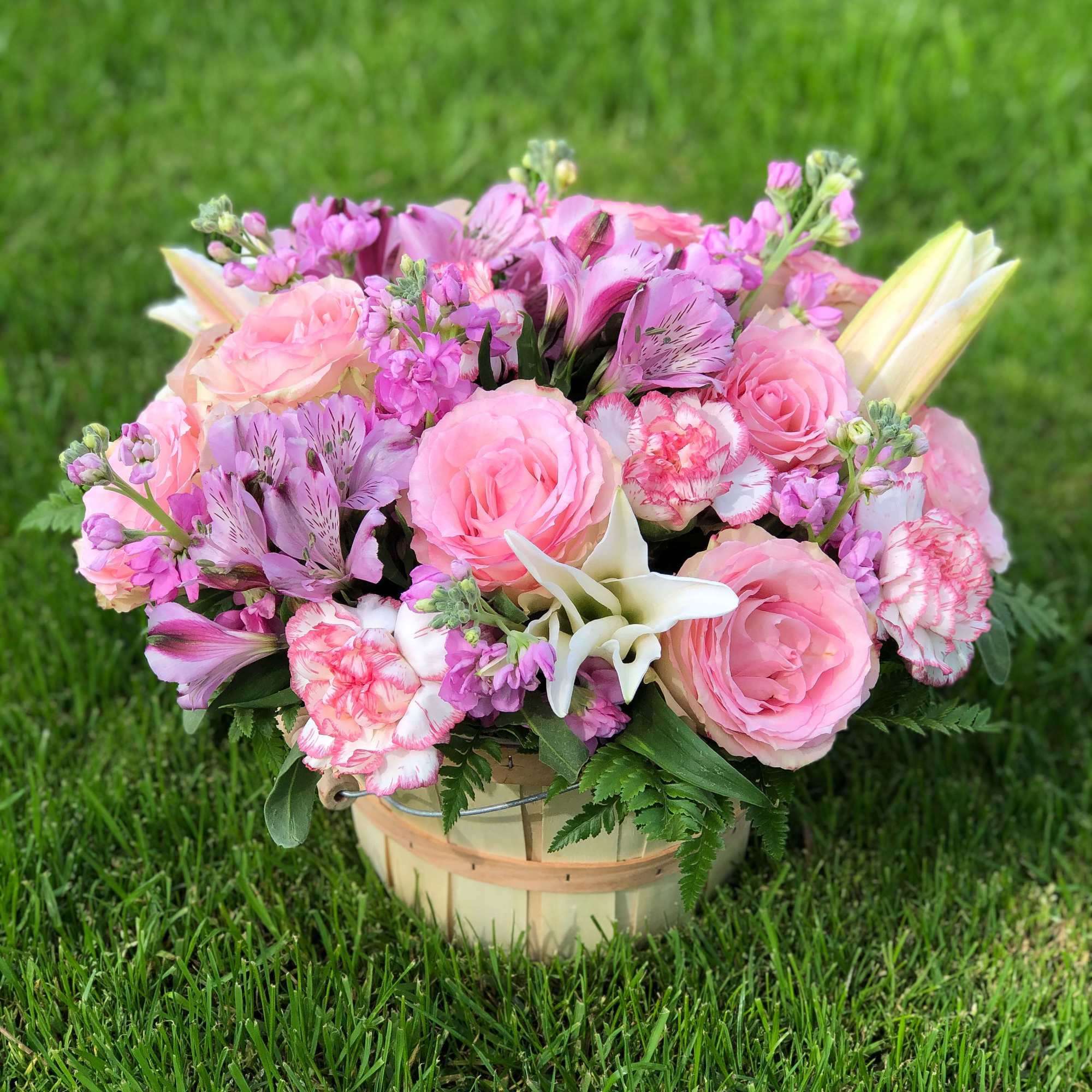 Pink and lavender flower arrangement in a wooden basket