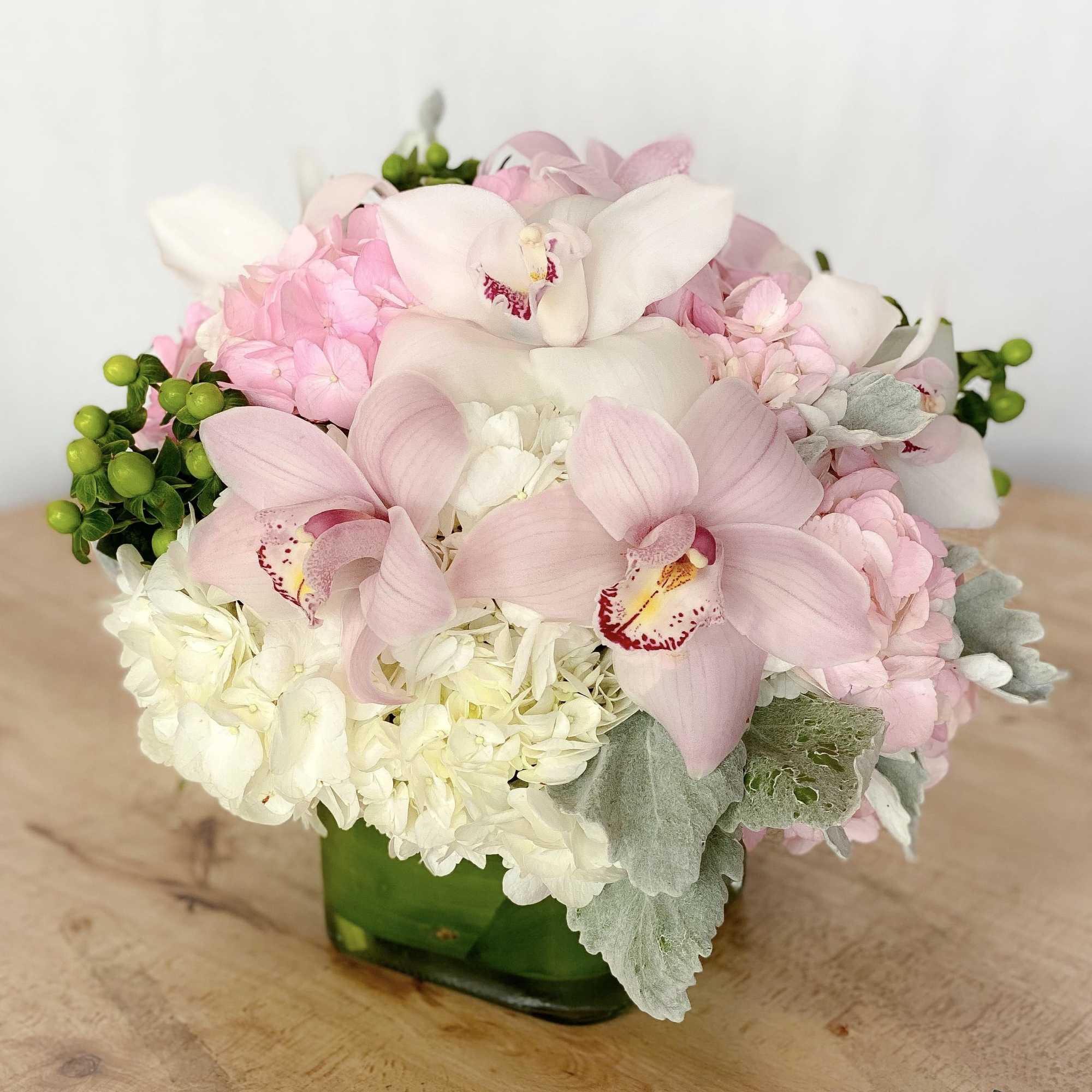 Pink and white orchid bouquet in a green glass vase