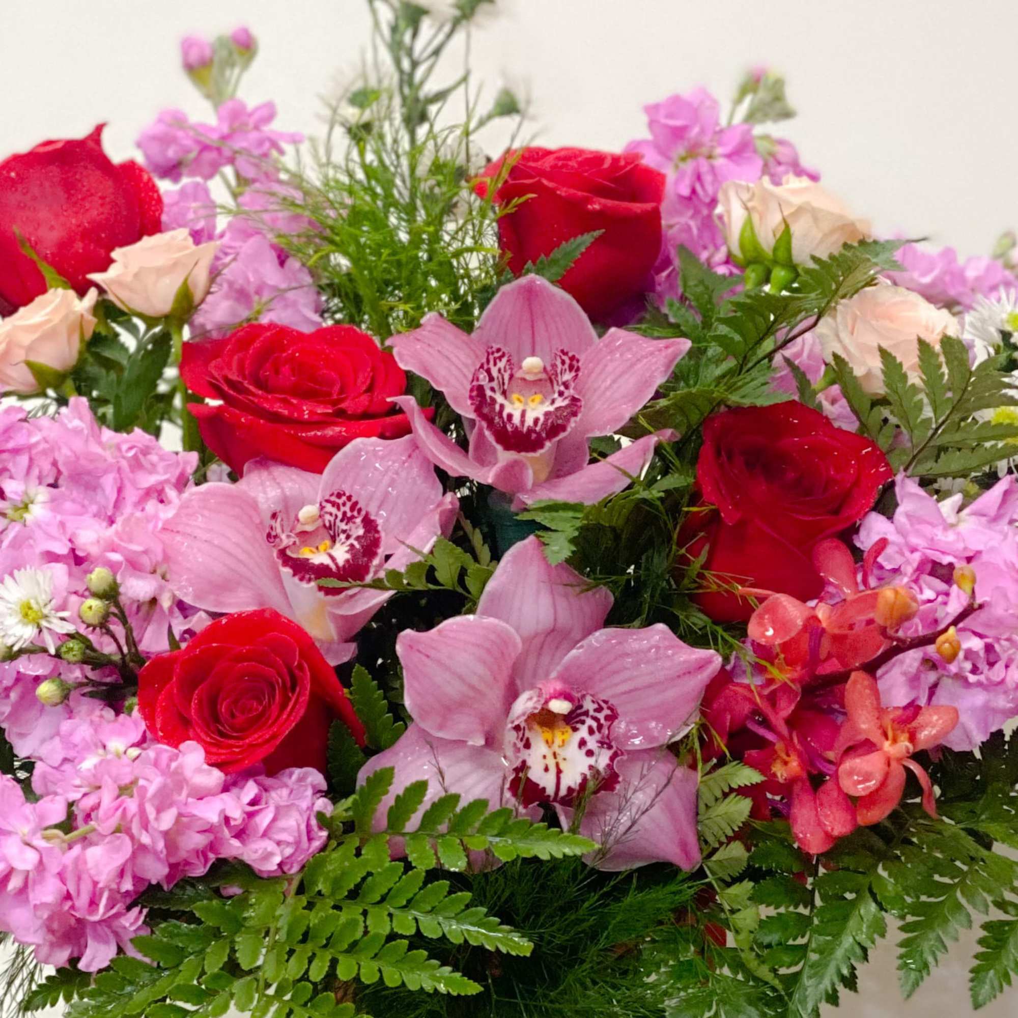 Bouquet of red roses, pink orchids, and pale pink flowers