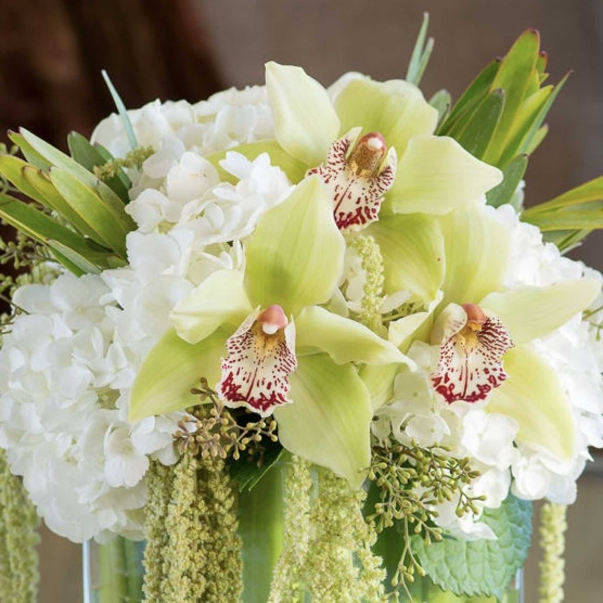 White hydrangeas and pale green orchids in a glass vase