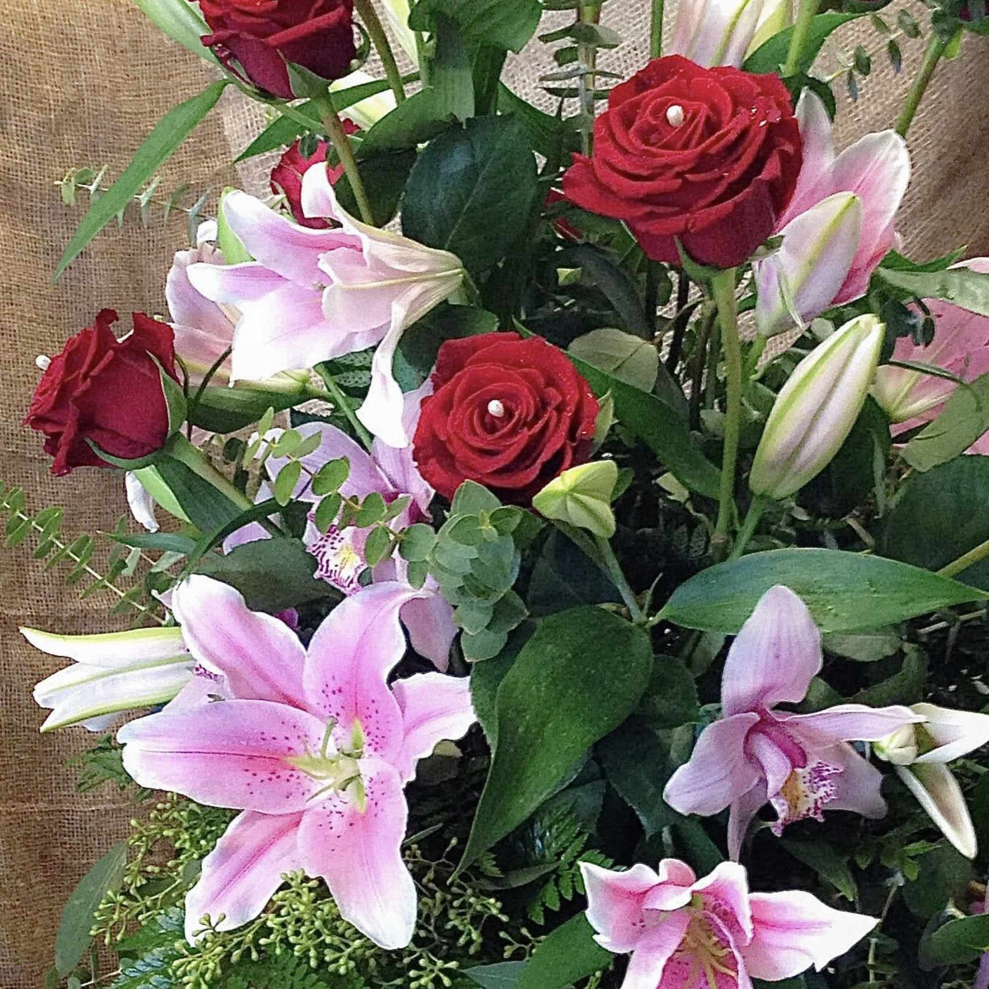 Bouquet of red roses and pink lilies with greenery