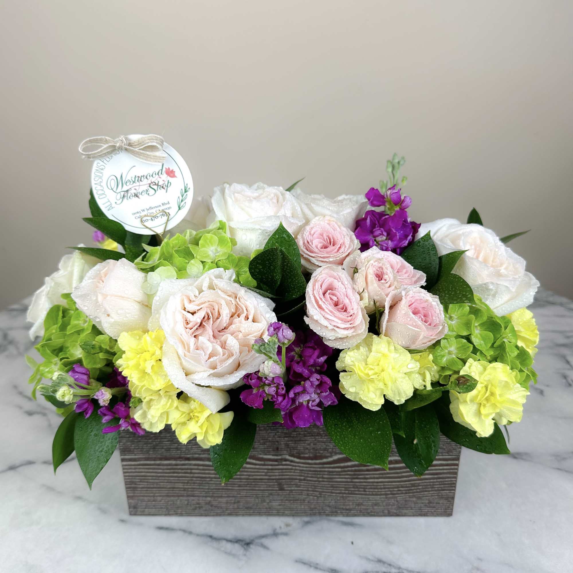 Mixed pink, white, yellow, and purple flowers in a rectangular wooden box