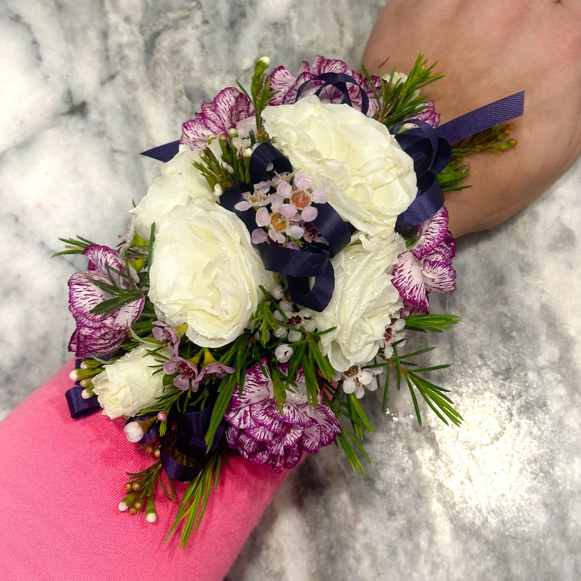 White and purple wrist corsage with ribbon on a wrist