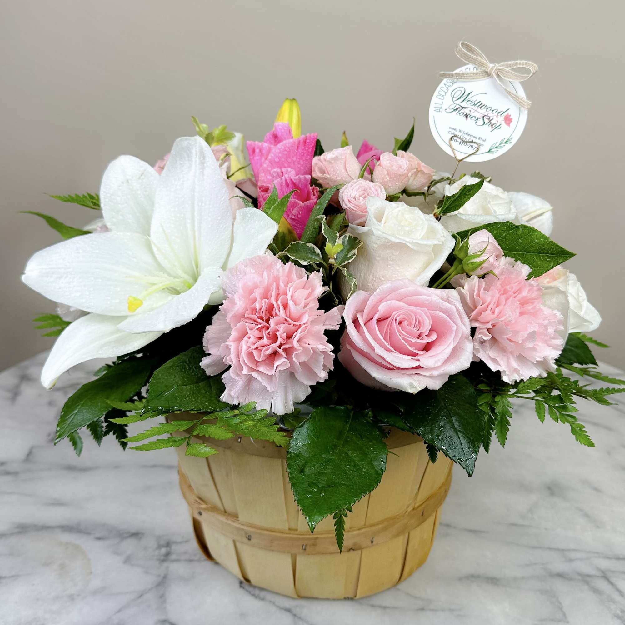 Pink and white flower arrangement in a wooden basket