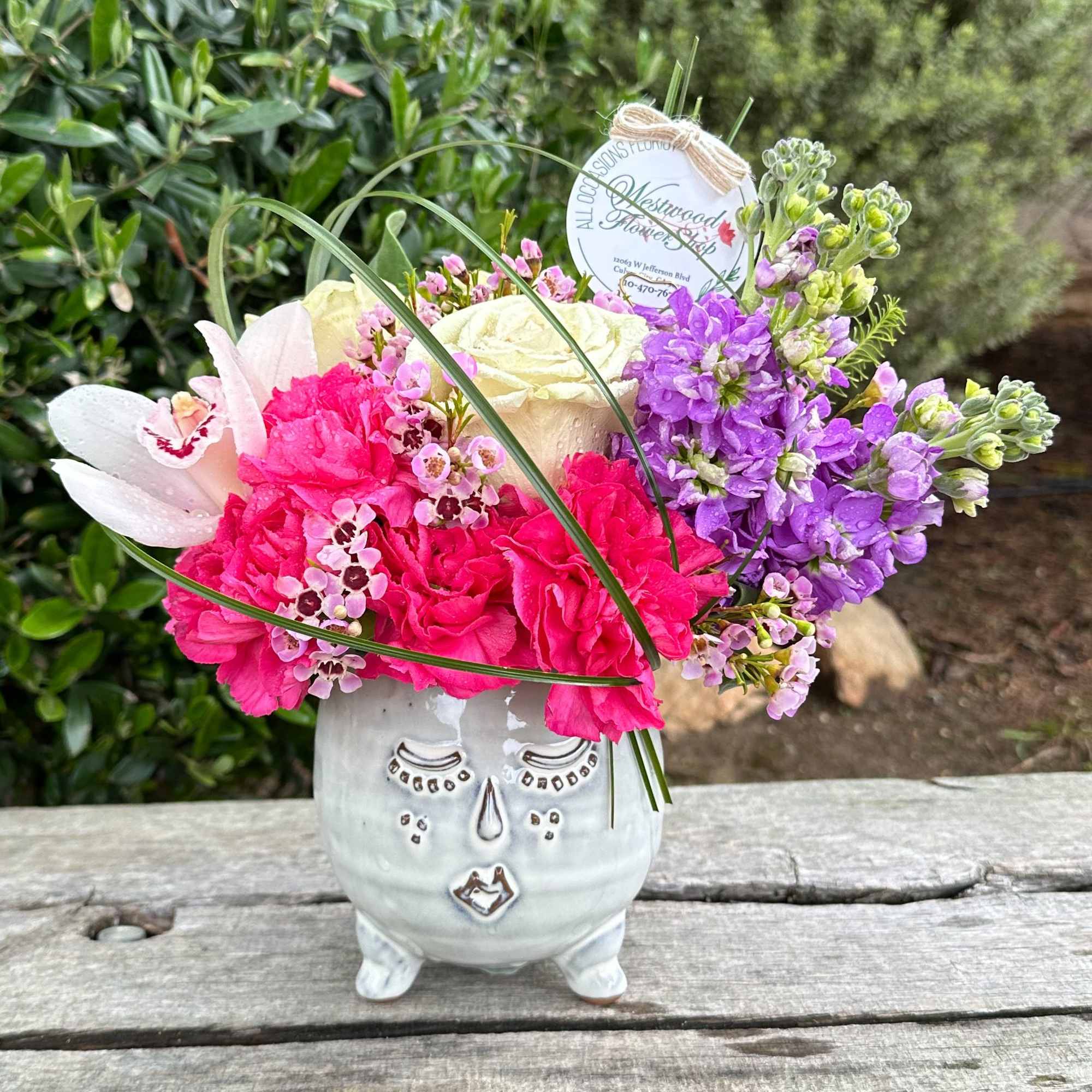 Pink and purple flowers arranged in a white face-shaped vase