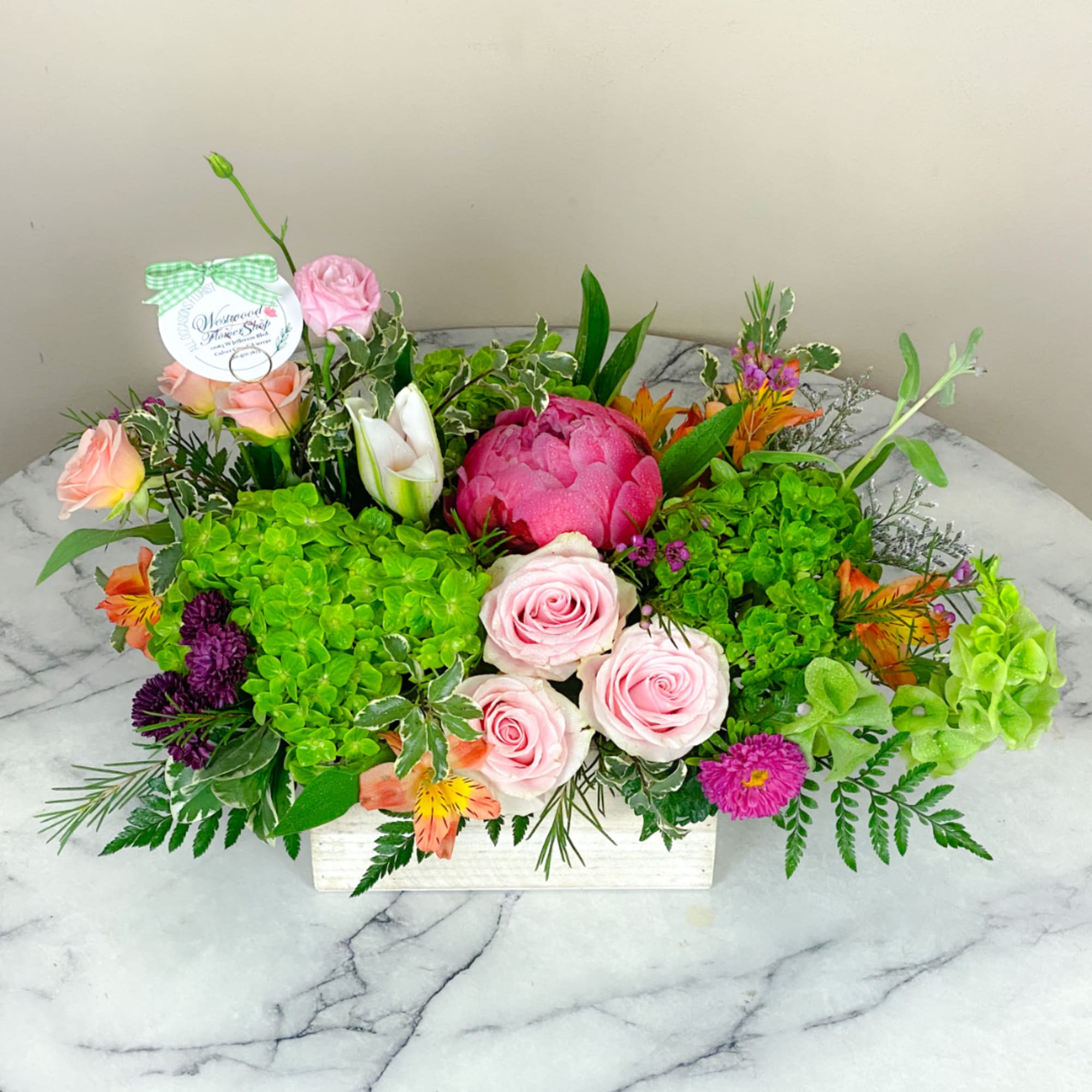 Pink roses and mixed flowers arranged in a white rectangular box