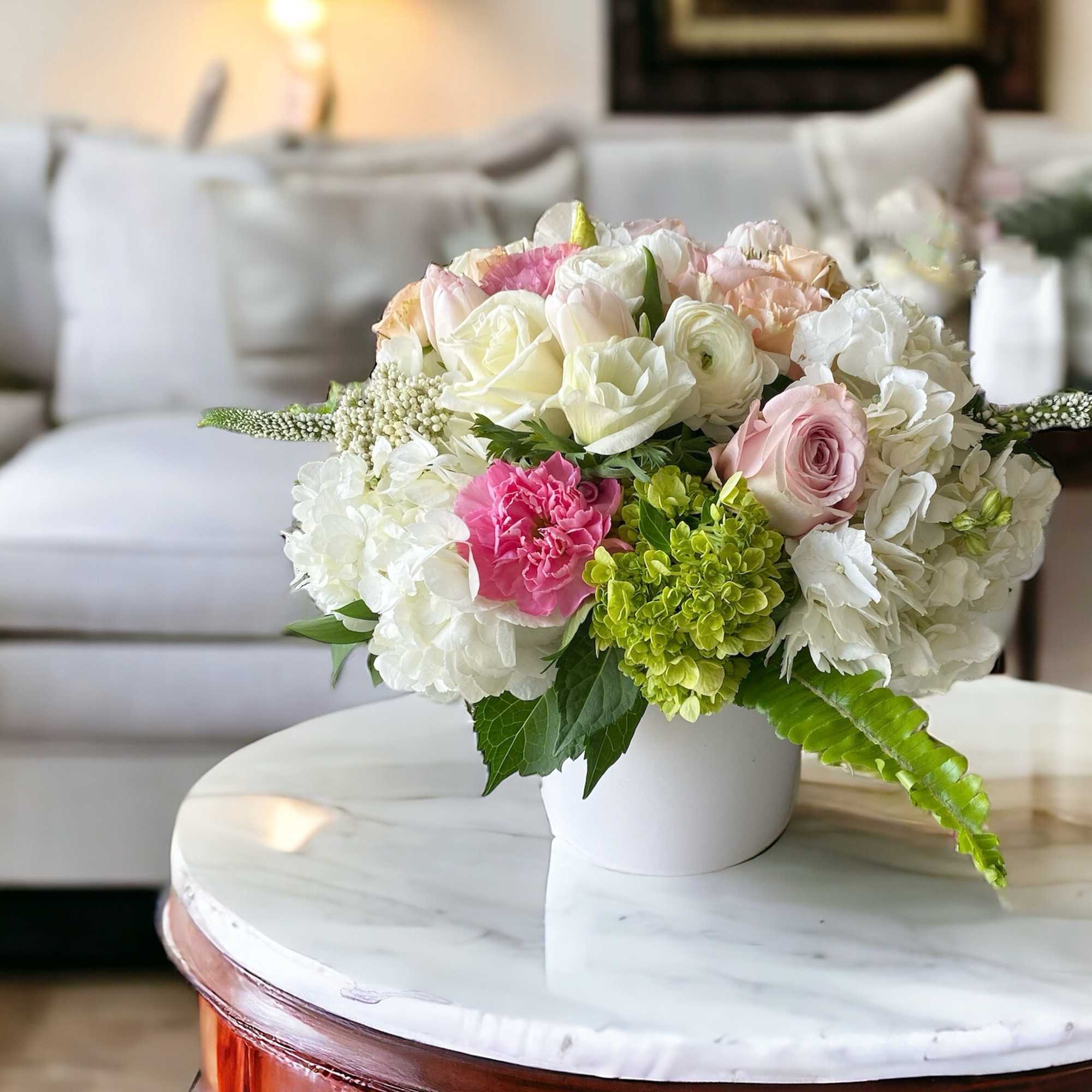 Pastel bouquet of roses, hydrangeas, and carnations in a white vase