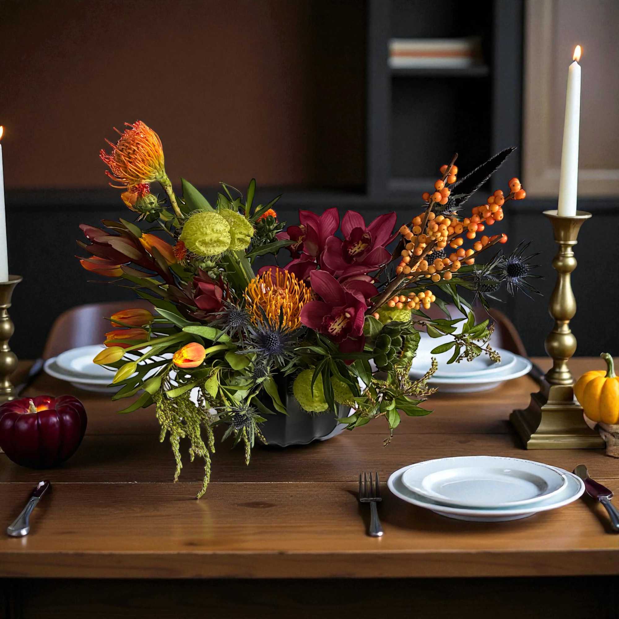 Autumn floral centerpiece with burgundy and orange blooms in a dark vase