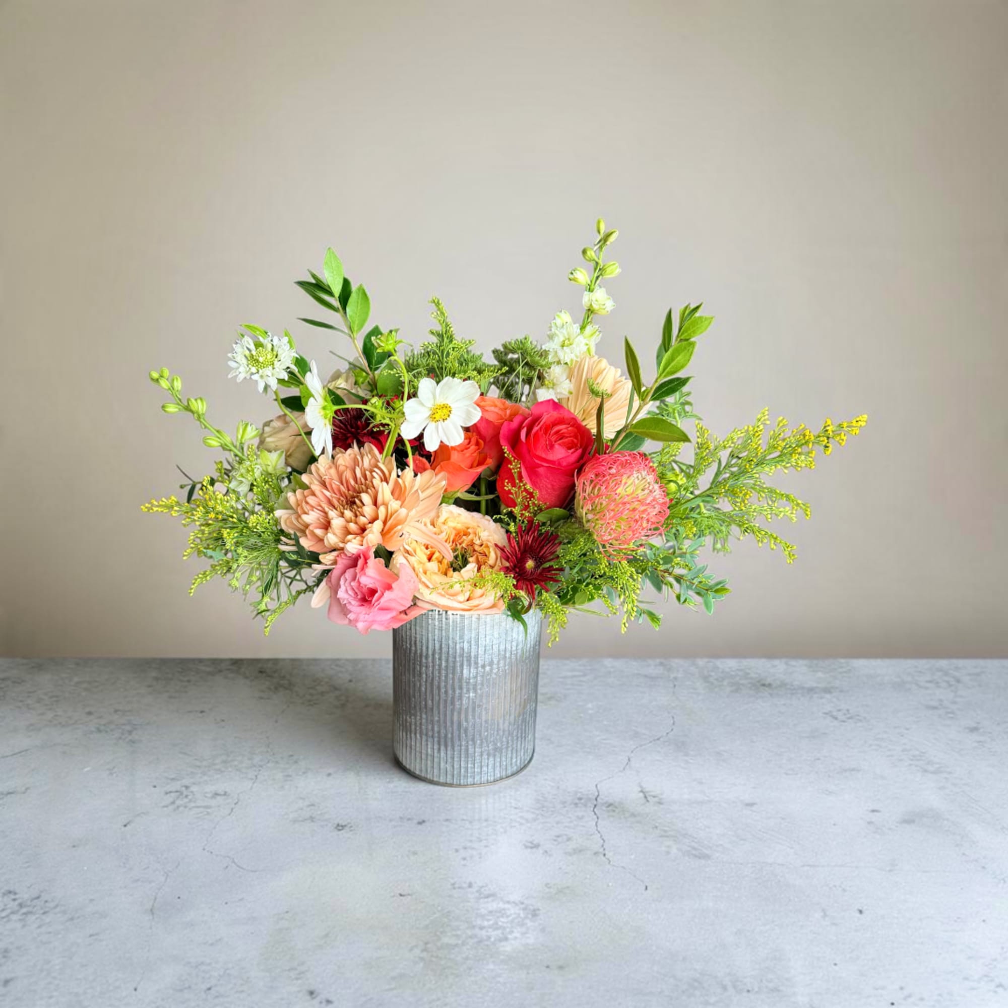 Mixed flower arrangement in a ribbed metal vase