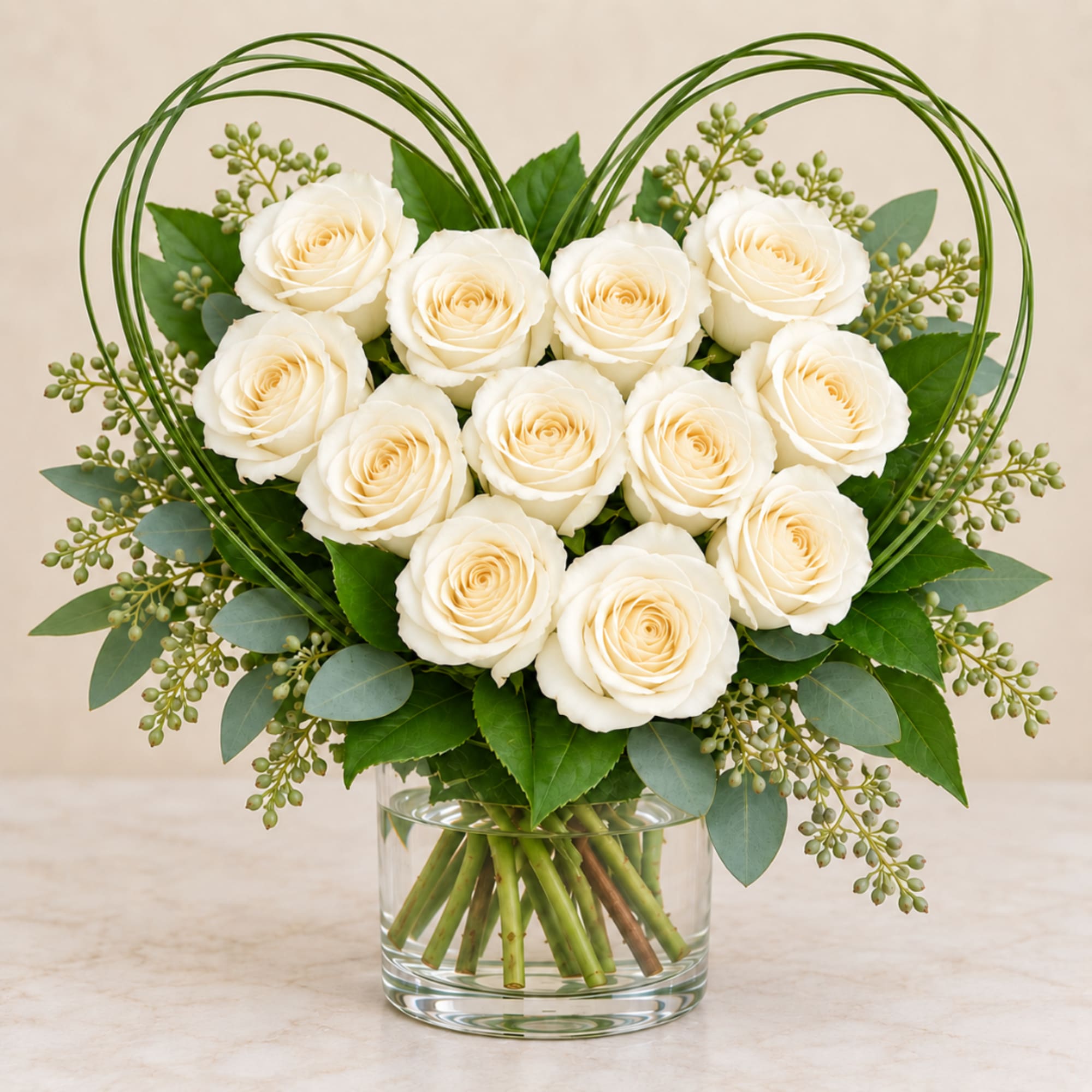 White roses arranged in a clear glass vase with a heart-shaped wire frame