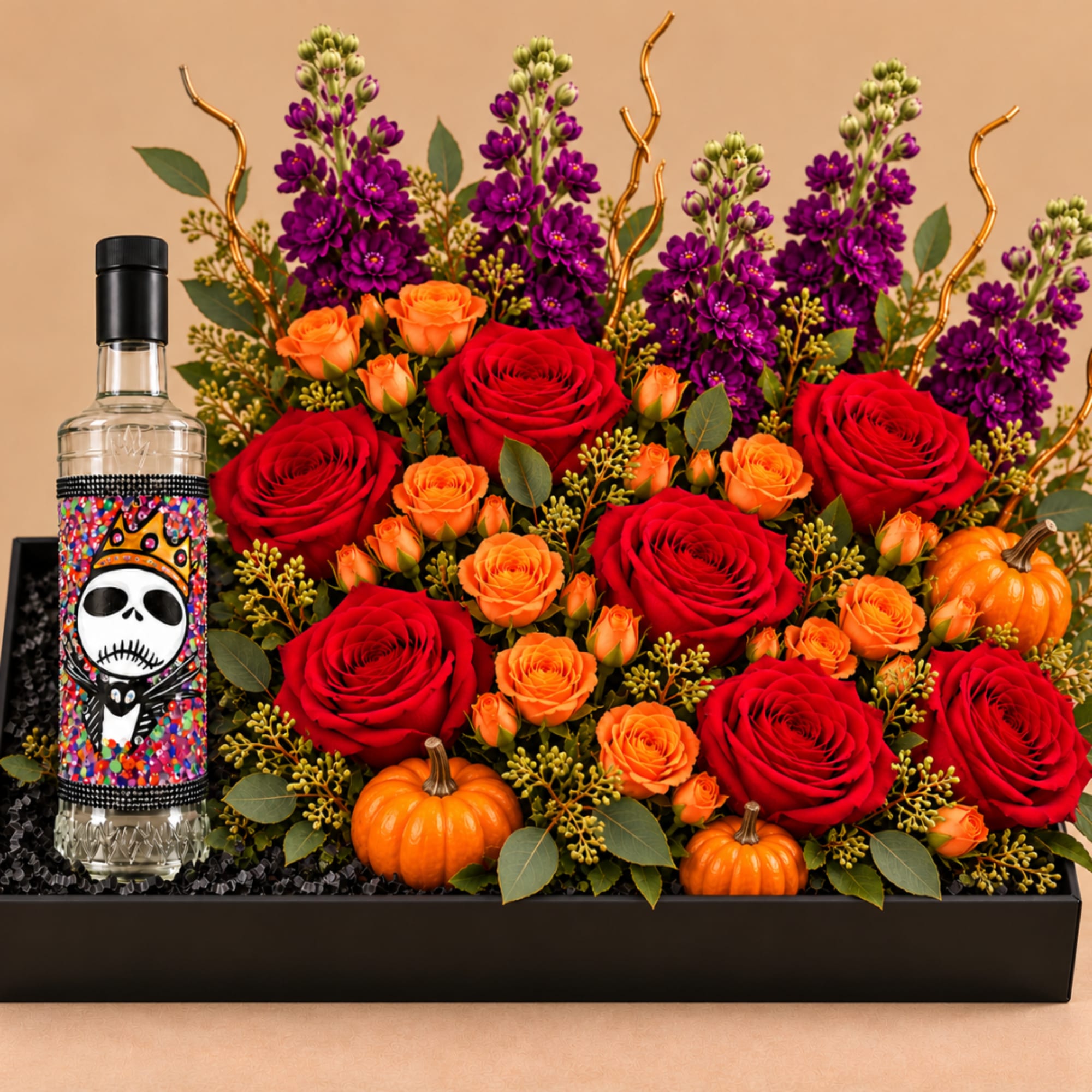 Red and orange roses with purple flowers in a black box, plus a decorated bottle and mini pumpkins
