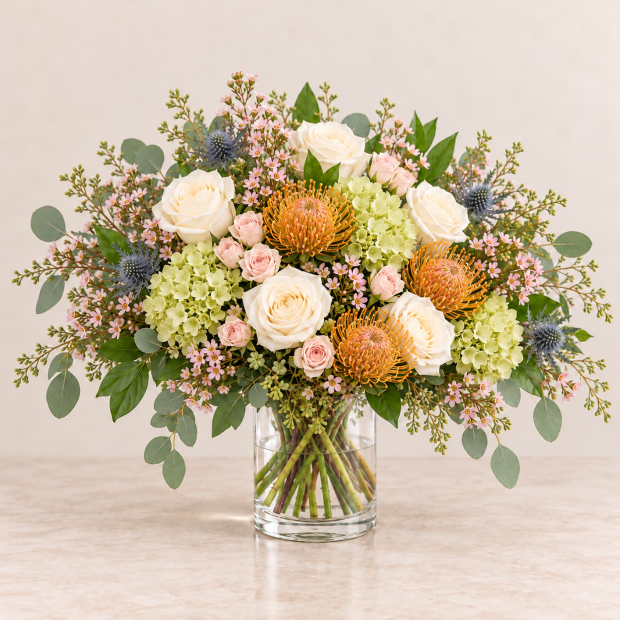 Mixed bouquet of white roses, pink blooms, and orange flowers in a glass vase