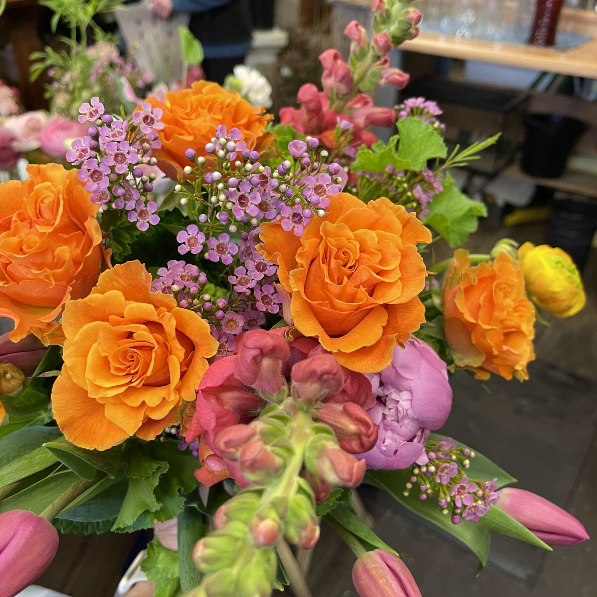 Bouquet of orange roses with pink snapdragons and purple filler flowers