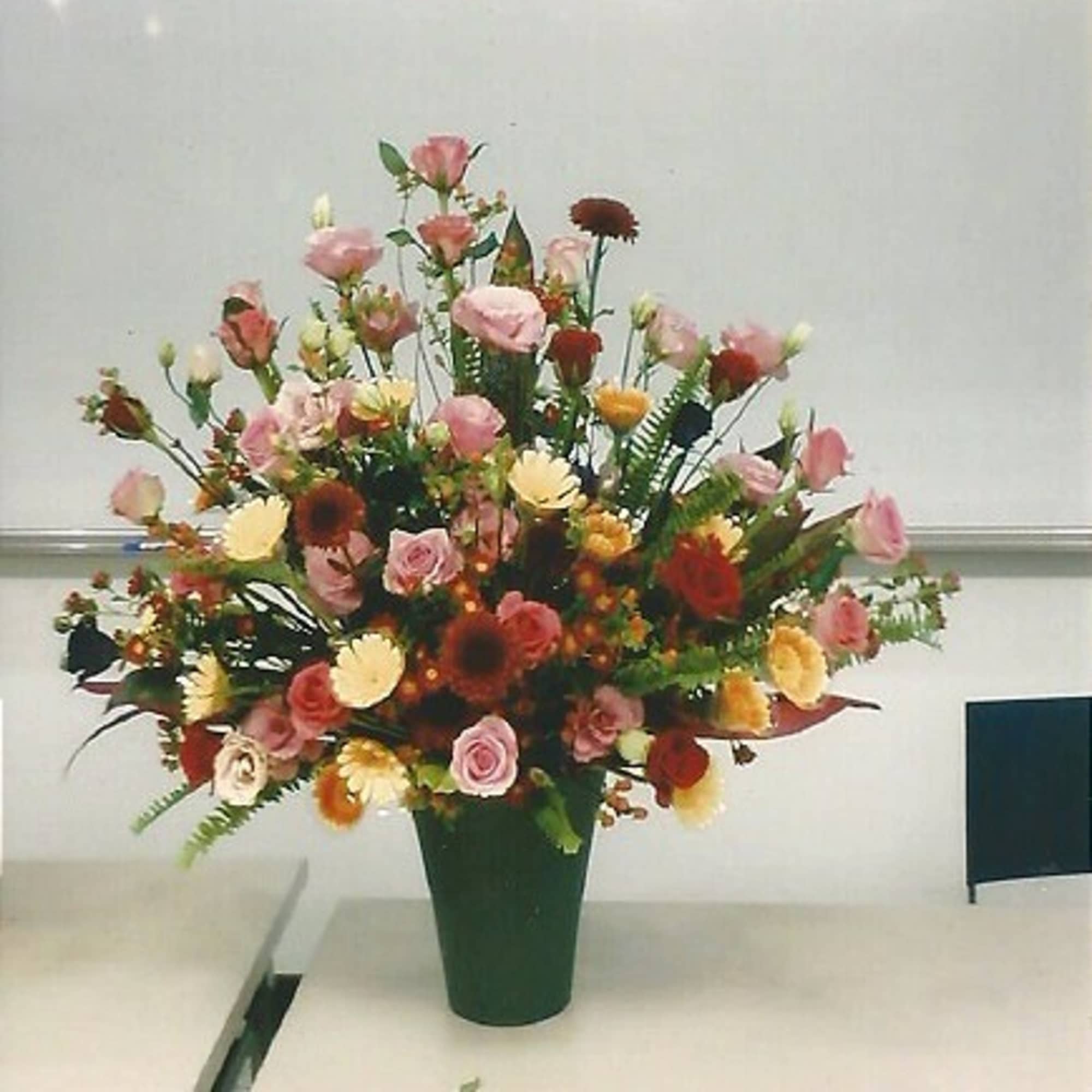 Mixed bouquet in a green vase with pink, red, and yellow flowers