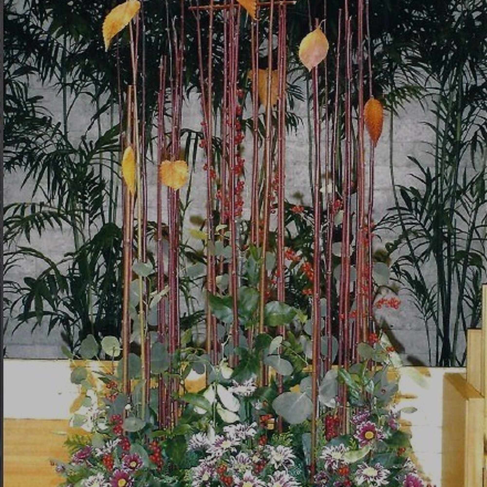 Tall floral arrangement with purple and white flowers in a black container