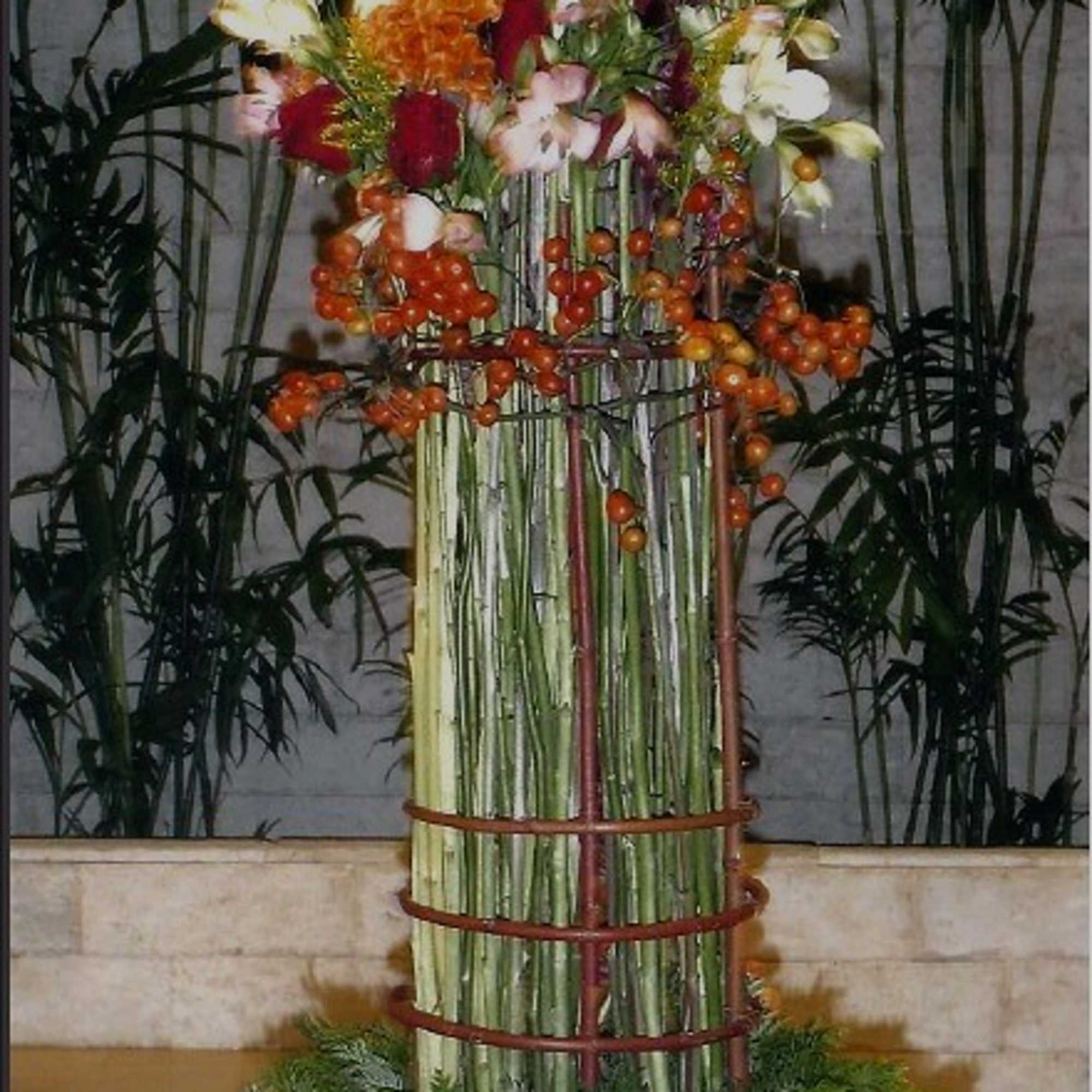 Tall floral arrangement with orange and white blooms in a metal stand