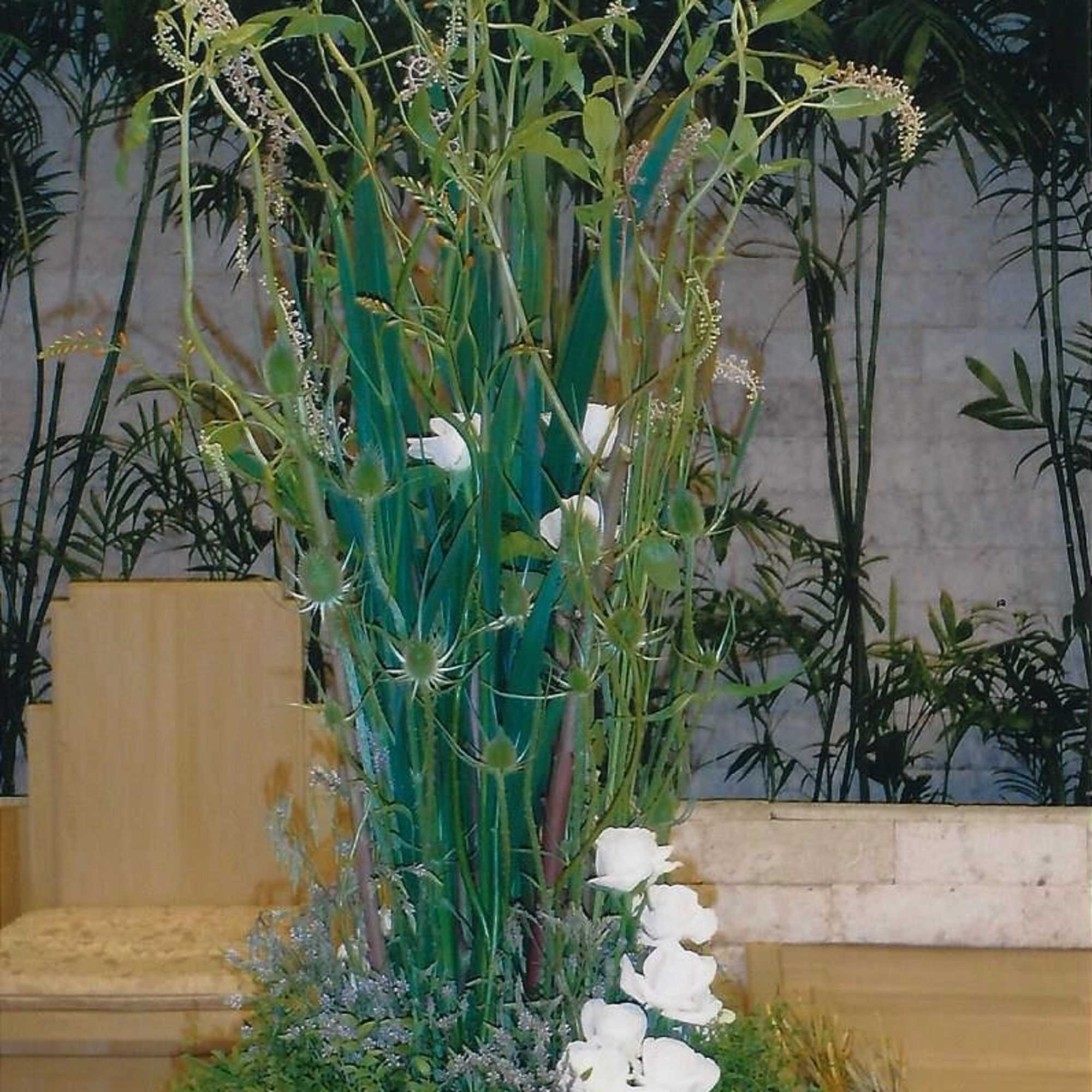 Tall floral arrangement with white blooms and green foliage in a low container