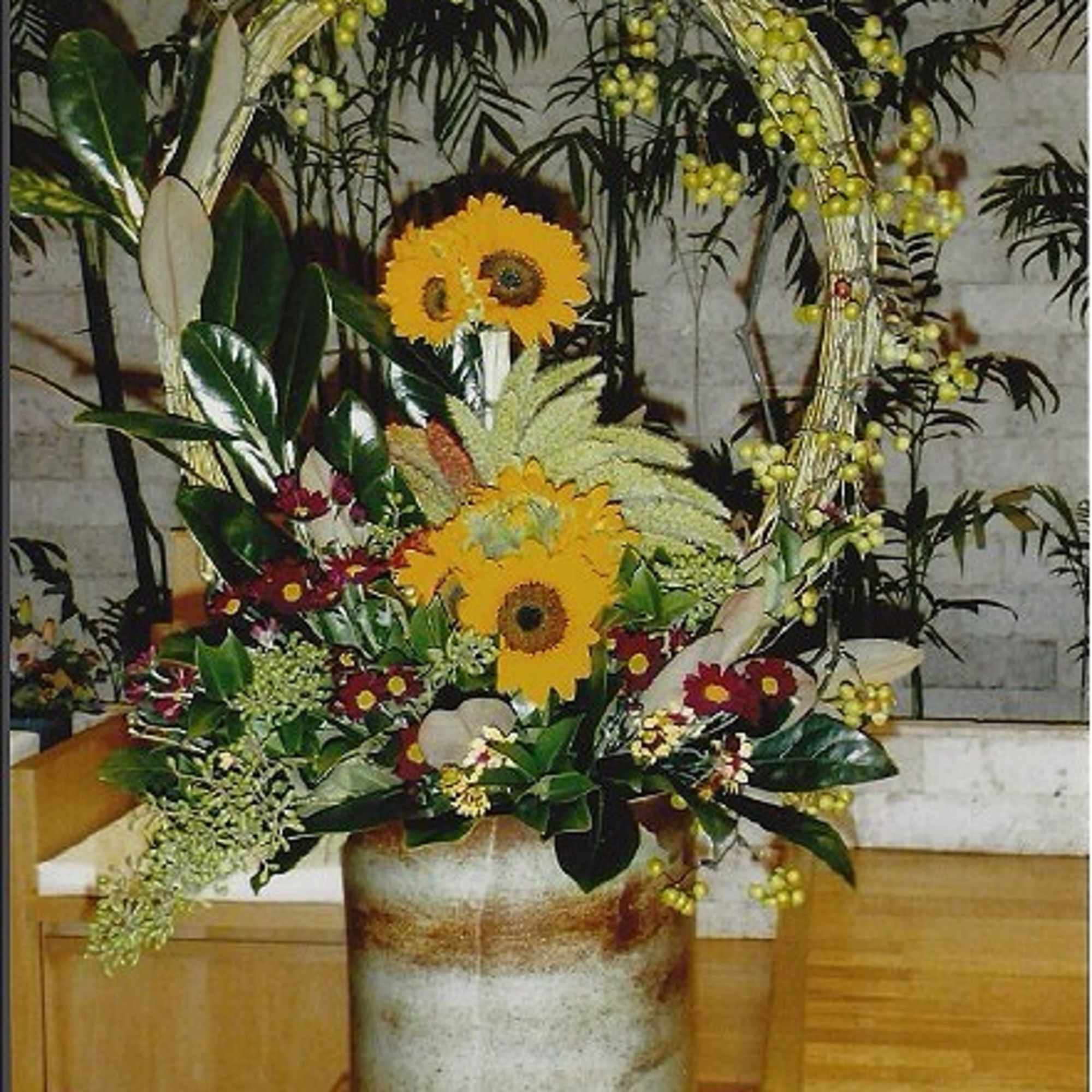 Tall floral arrangement with yellow gerbera daisies in a metal vase