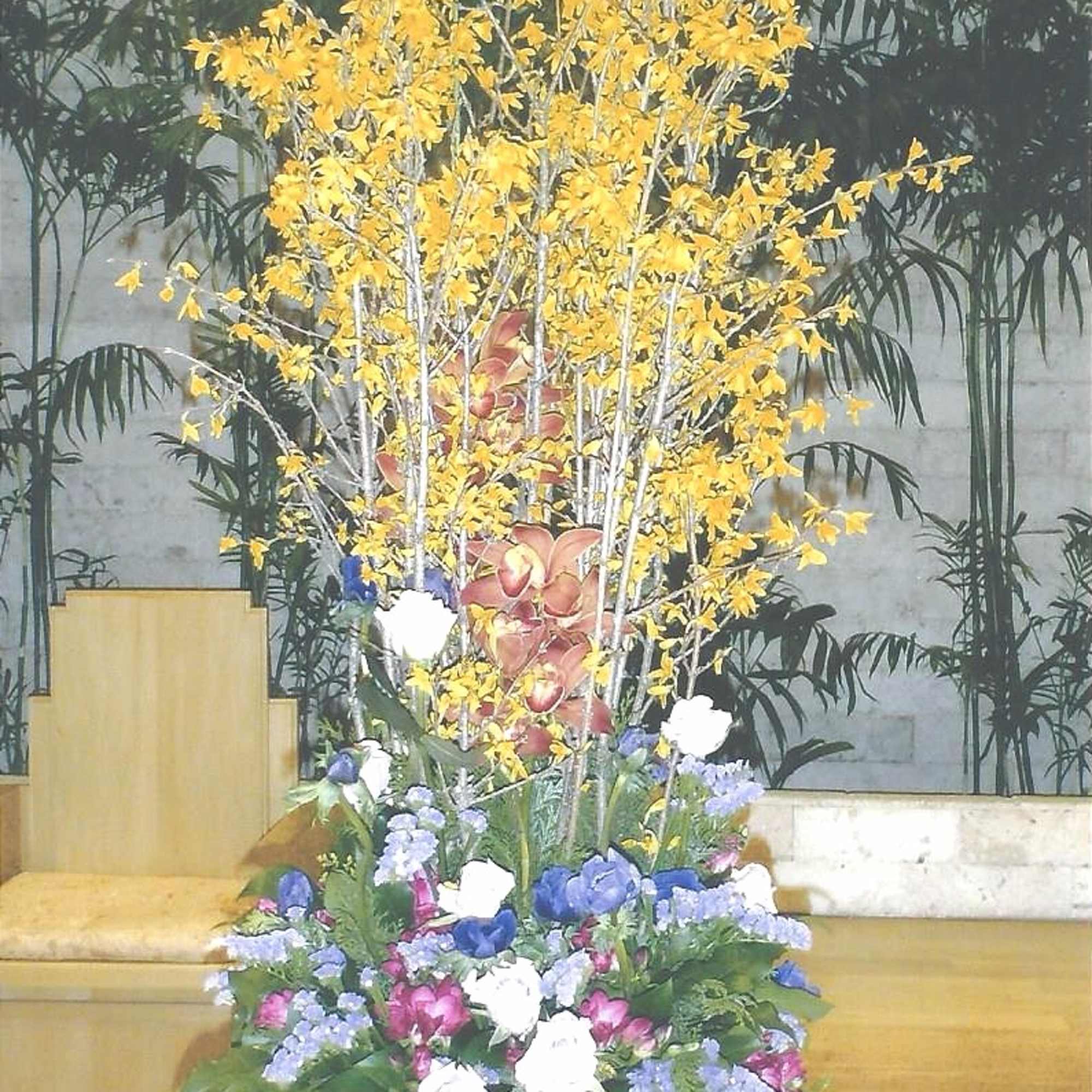Tall floral arrangement with yellow blossoms and mixed purple, white, and pink flowers