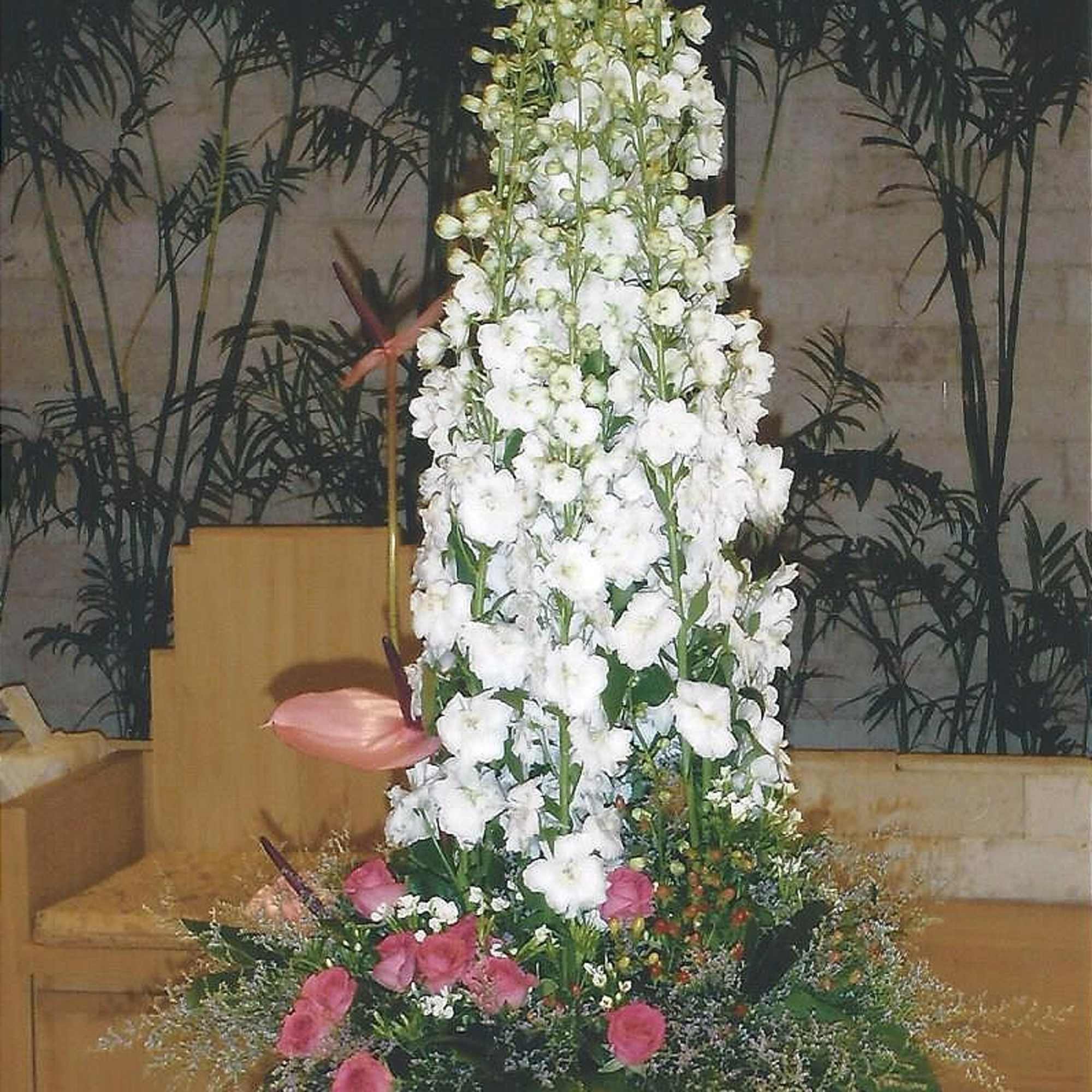 Tall white floral arrangement with pink accents in a container
