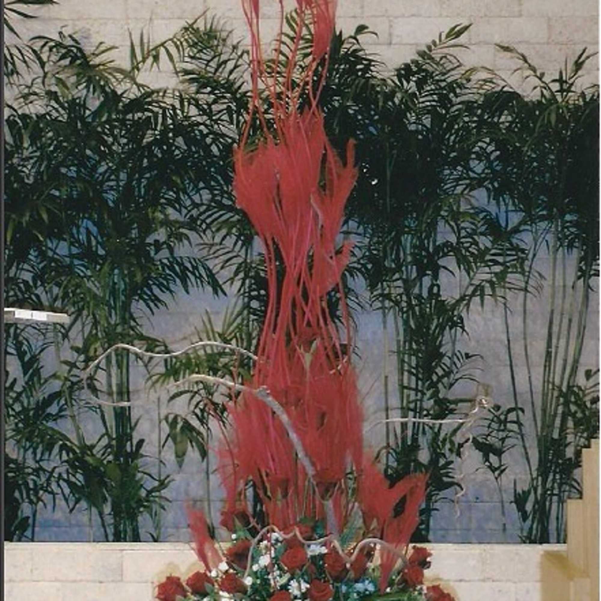Tall red floral arrangement with roses and white daisies in a round container