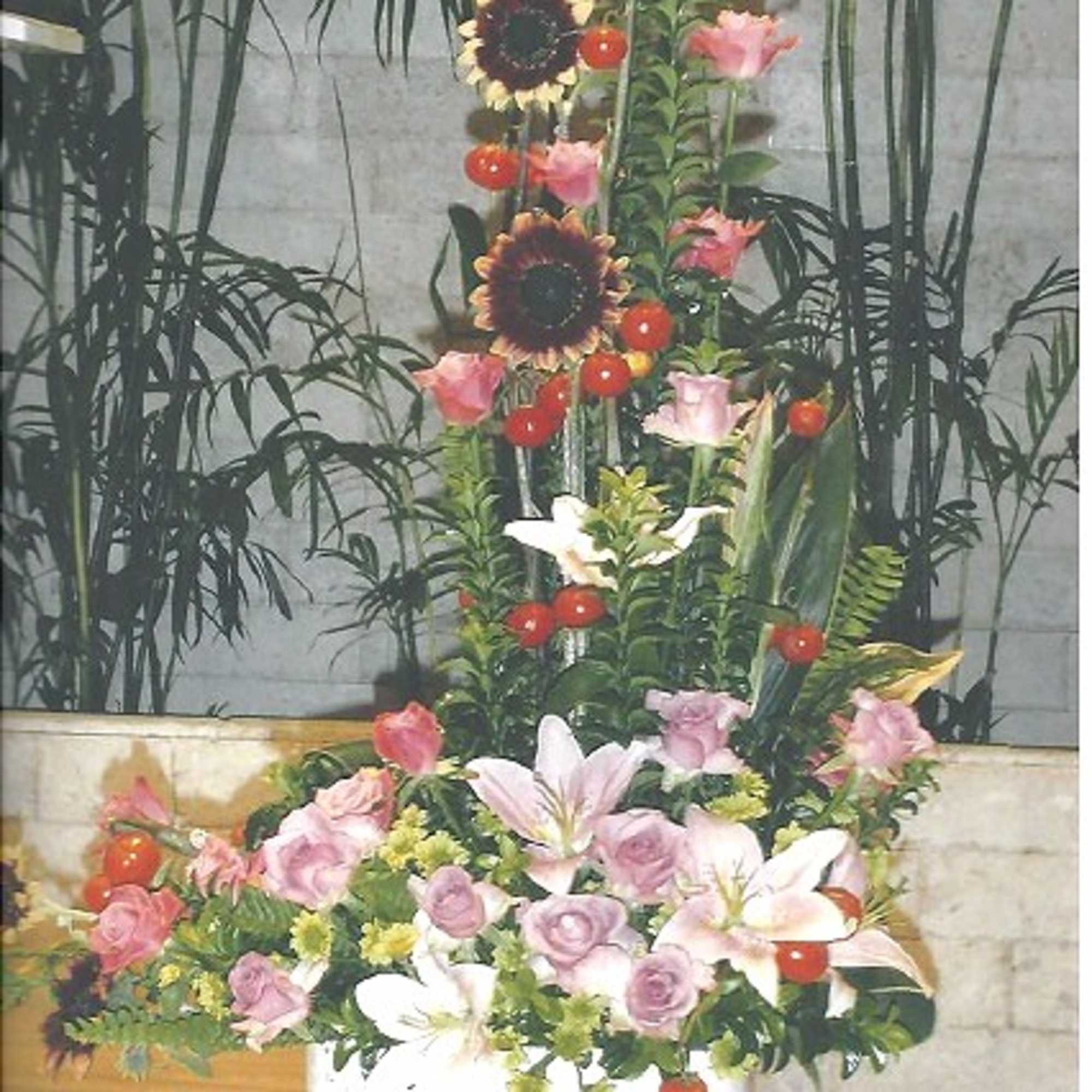 Tall floral arrangement with pink lilies and roses in a white container