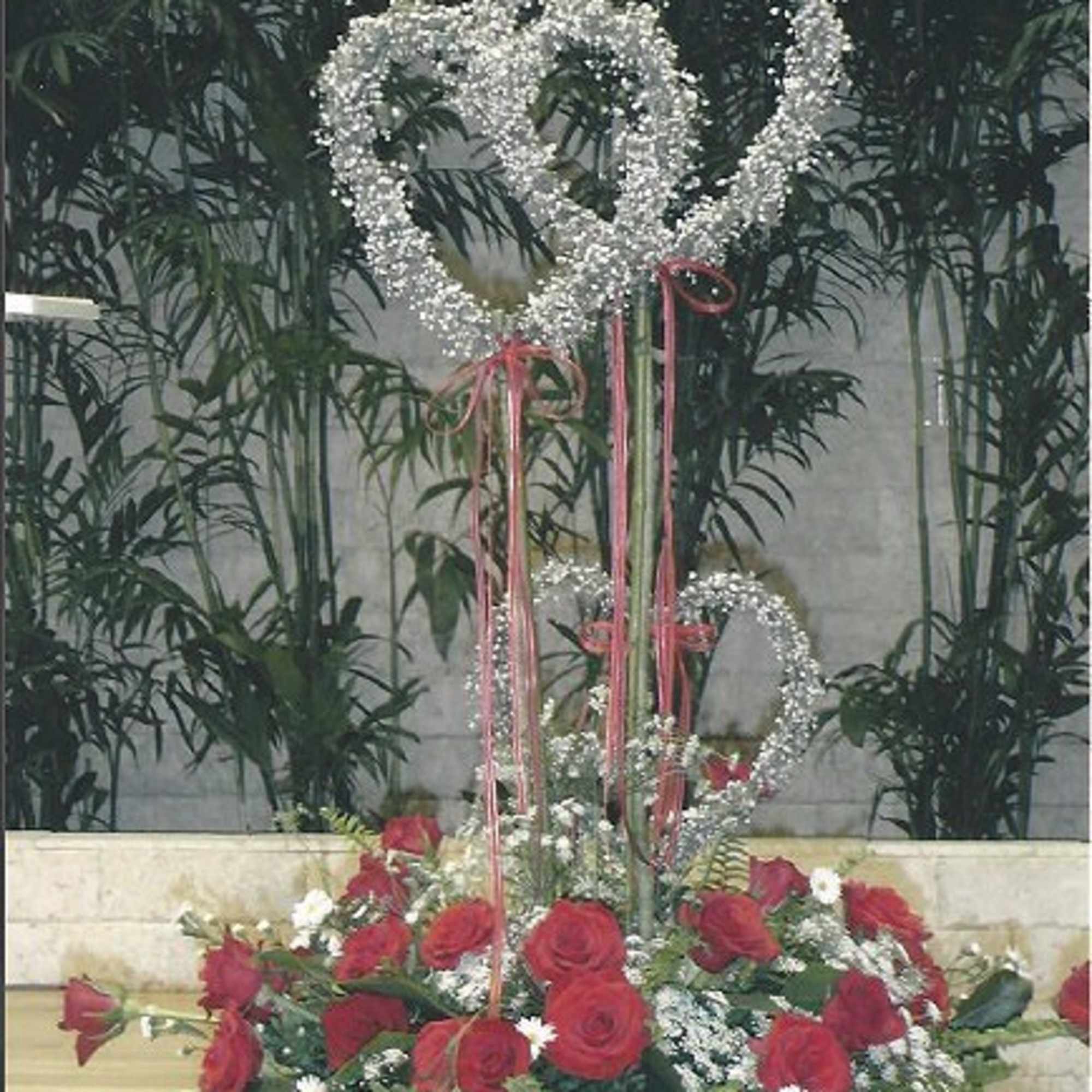 Red roses in a white vase with silver heart decorations and pink ribbons
