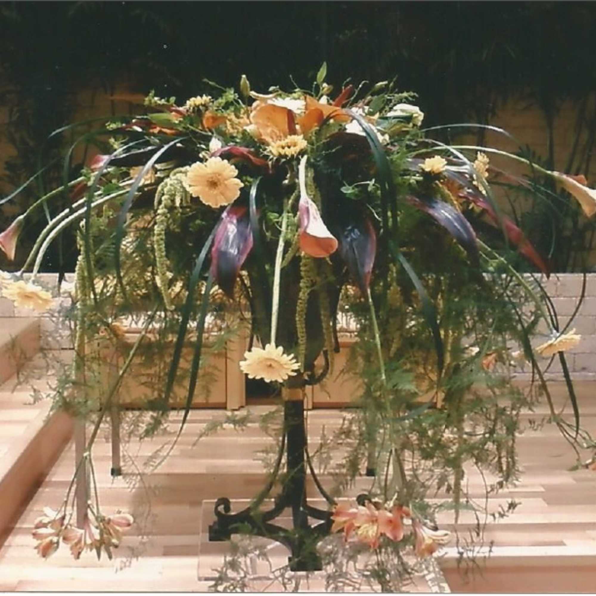 Large cascading floral arrangement on a stand with orange and cream flowers