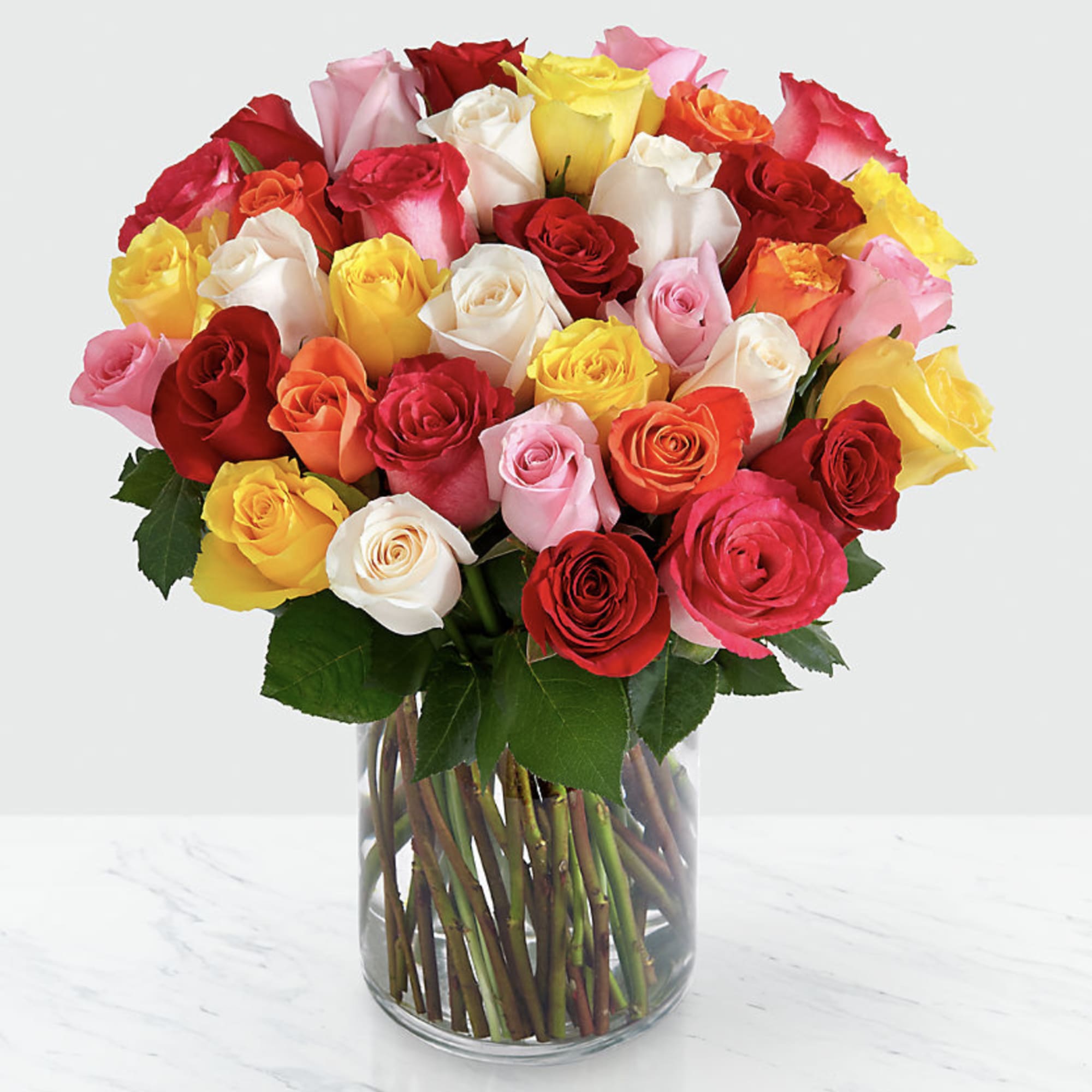 Mixed roses in red, pink, white, yellow, and orange in a glass vase