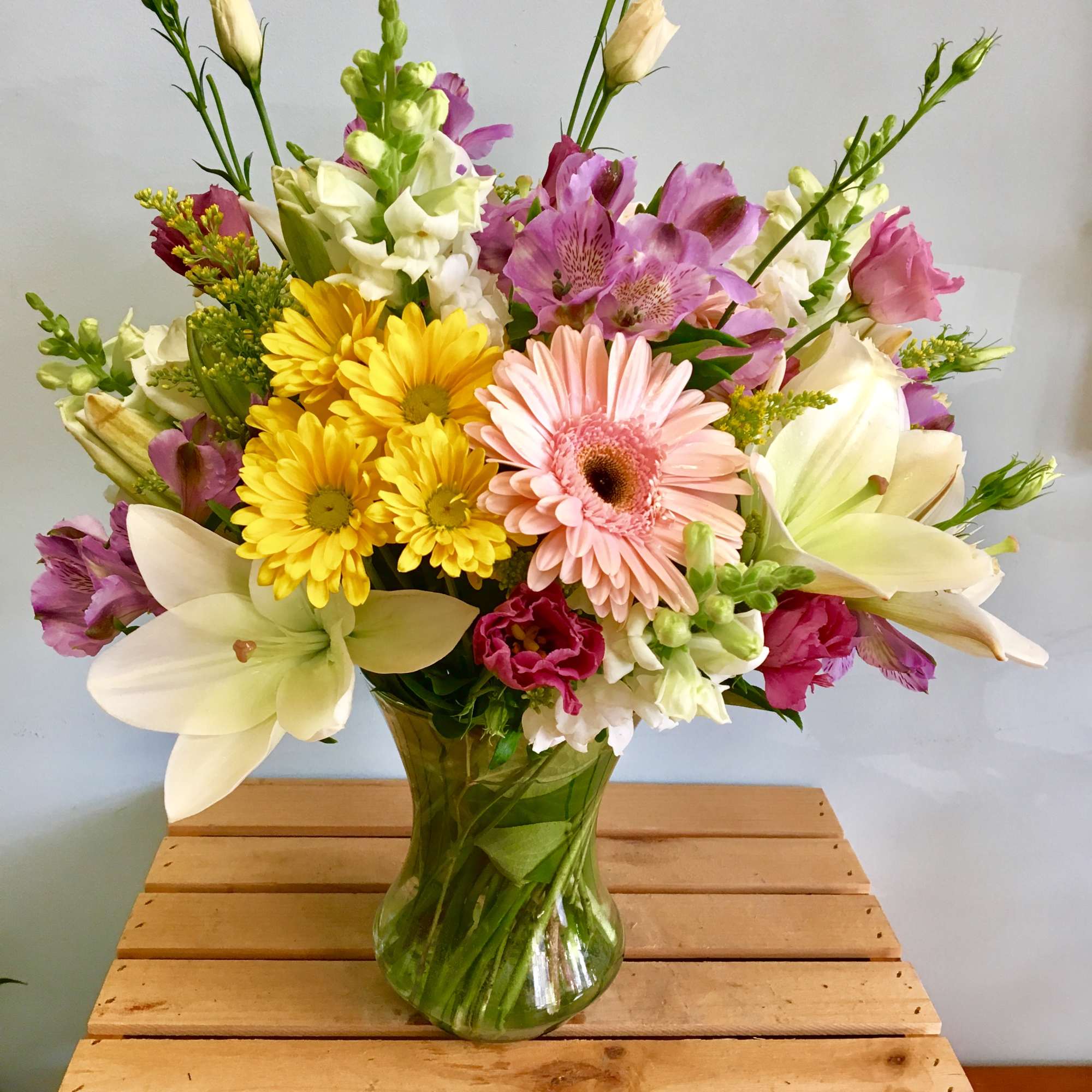 Mixed bouquet of pink, yellow, and white flowers in a glass vase