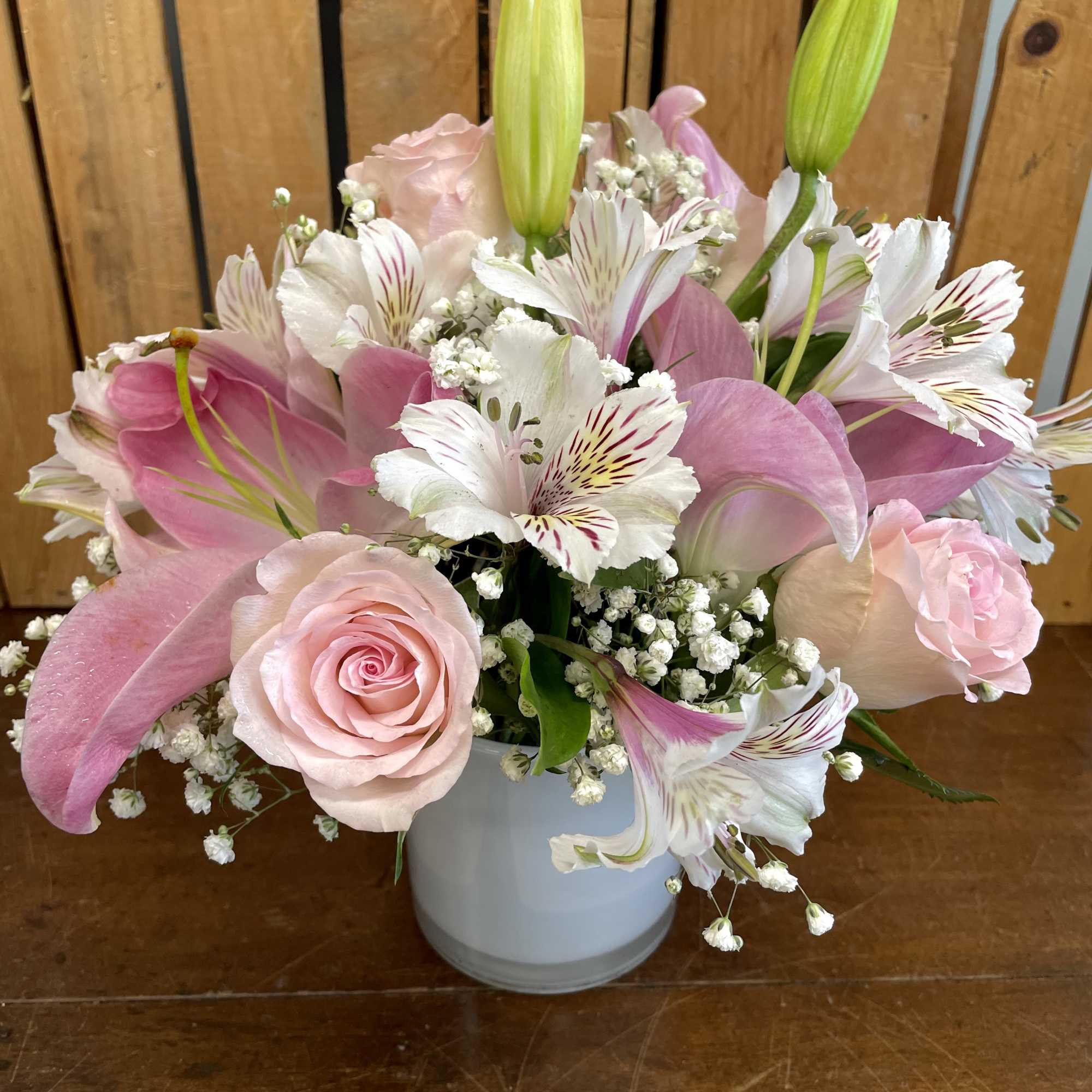 Pink roses and lilies arranged in a white vase