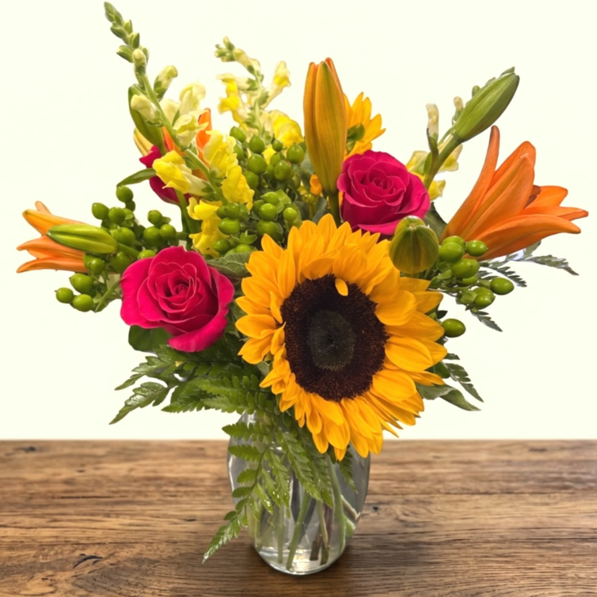 Sunflower and pink rose bouquet in a clear glass vase