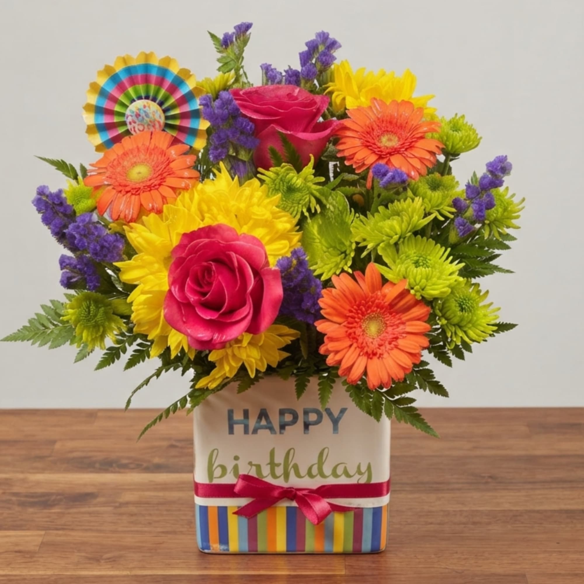 Bright mixed flower arrangement in a birthday tin with a ribbon