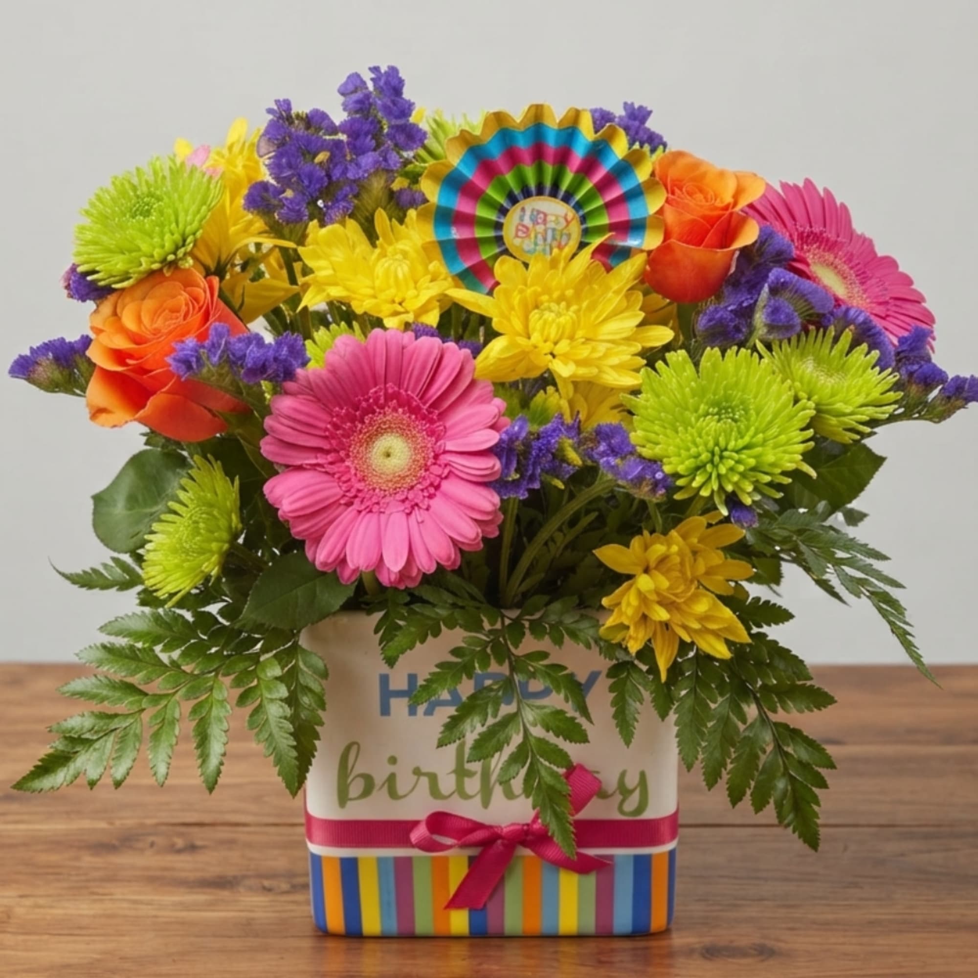 Colorful mixed flower arrangement in a striped birthday box with a ribbon
