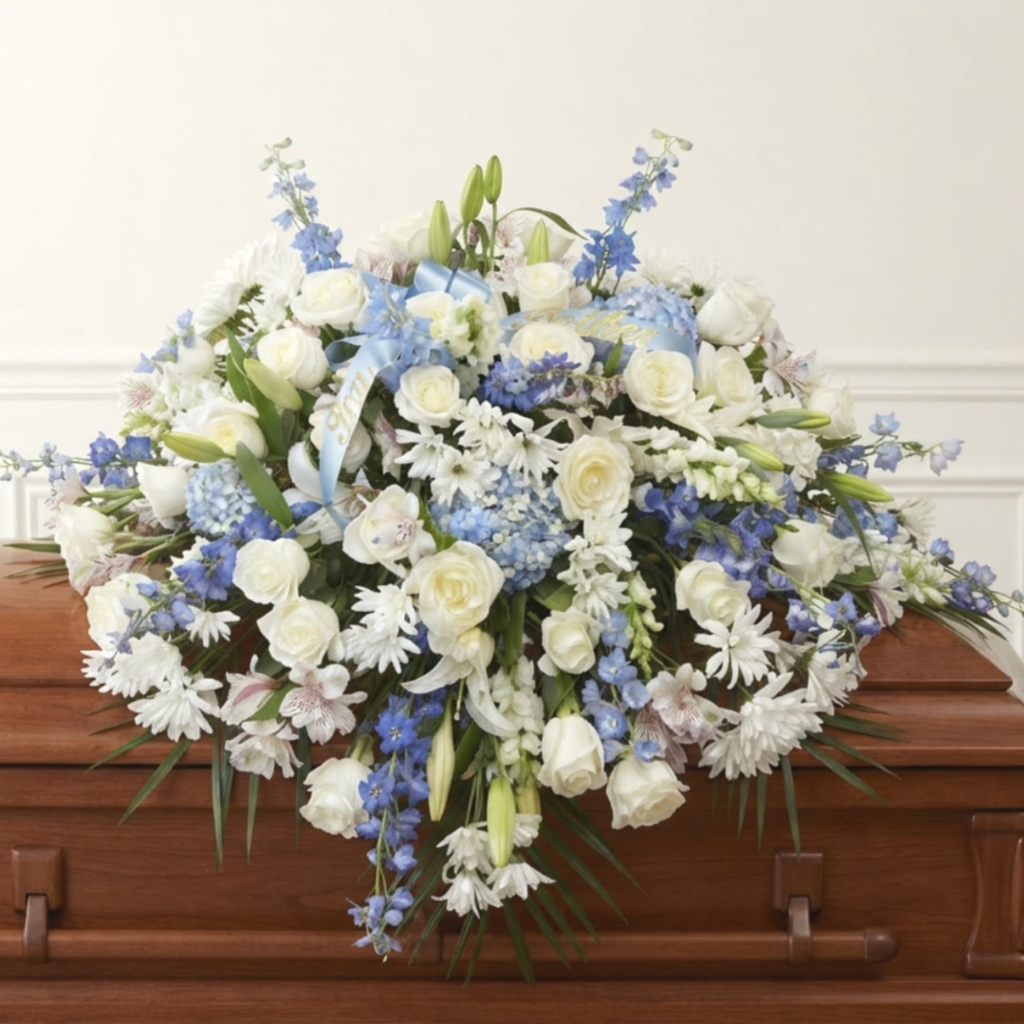 White and blue floral spray on a wooden casket
