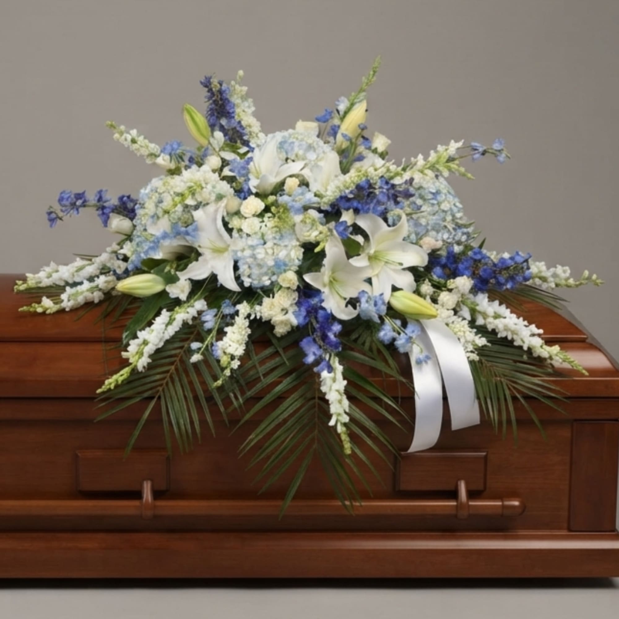 White and blue floral spray on a wooden casket