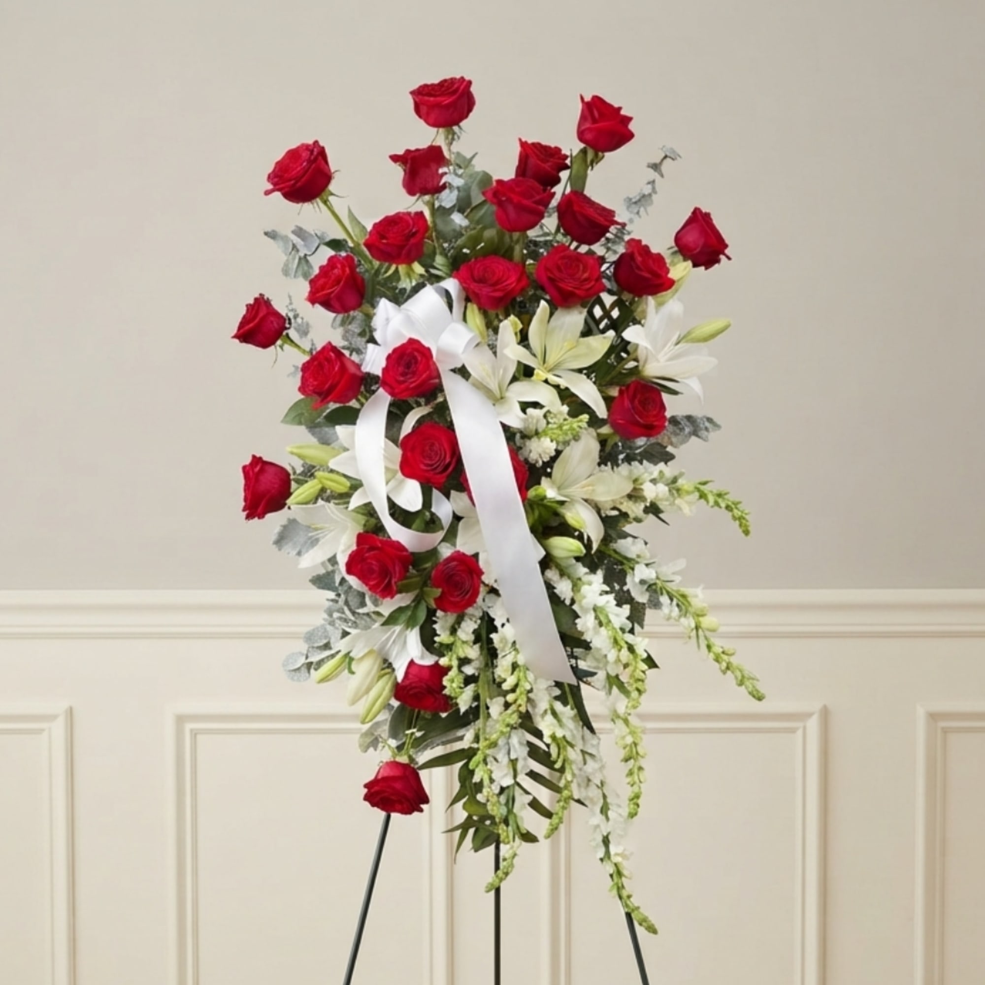 Standing floral spray with red roses, white lilies, and a white ribbon