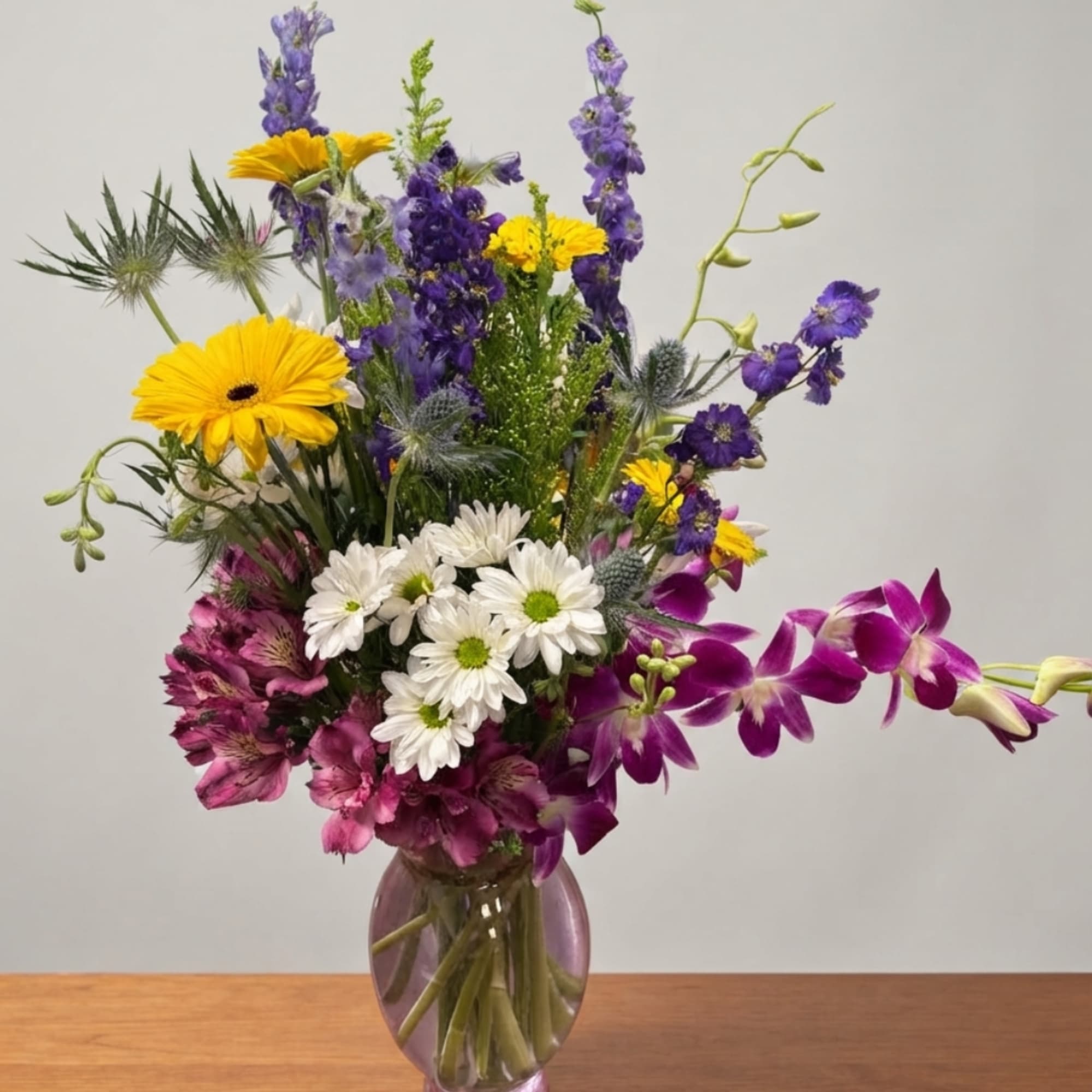 Mixed bouquet of purple, yellow, and white flowers in a glass vase