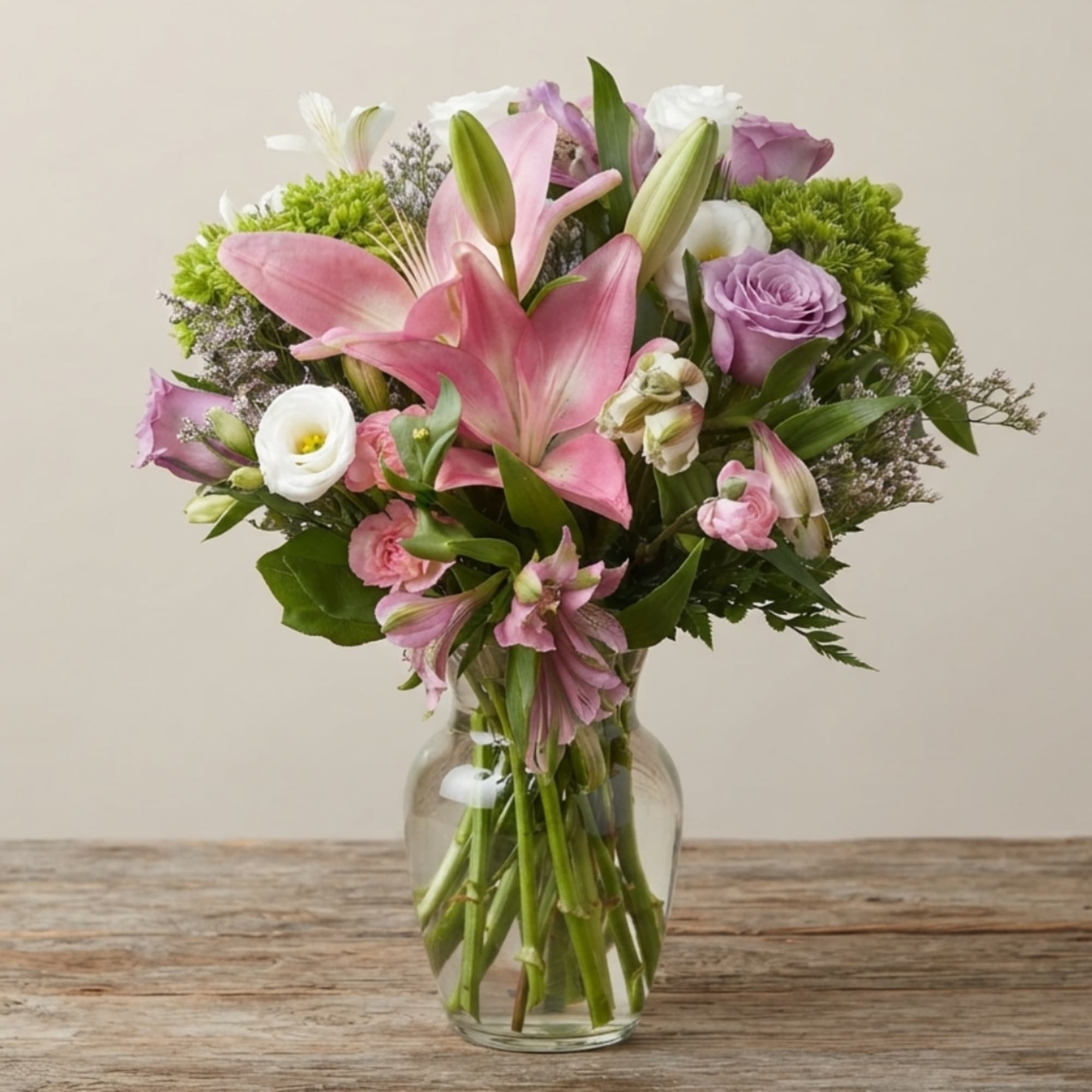 Pink lilies and lavender roses in a clear glass vase