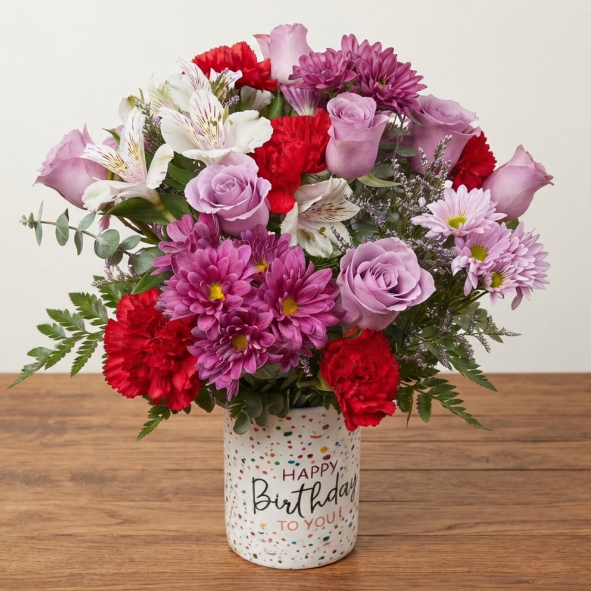 Mixed pink, purple, and red bouquet in a birthday vase