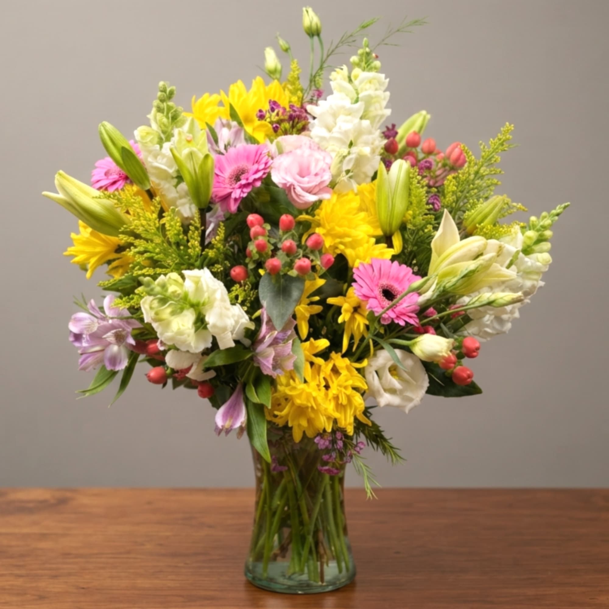 Mixed bouquet of yellow, pink, and white flowers in a glass vase